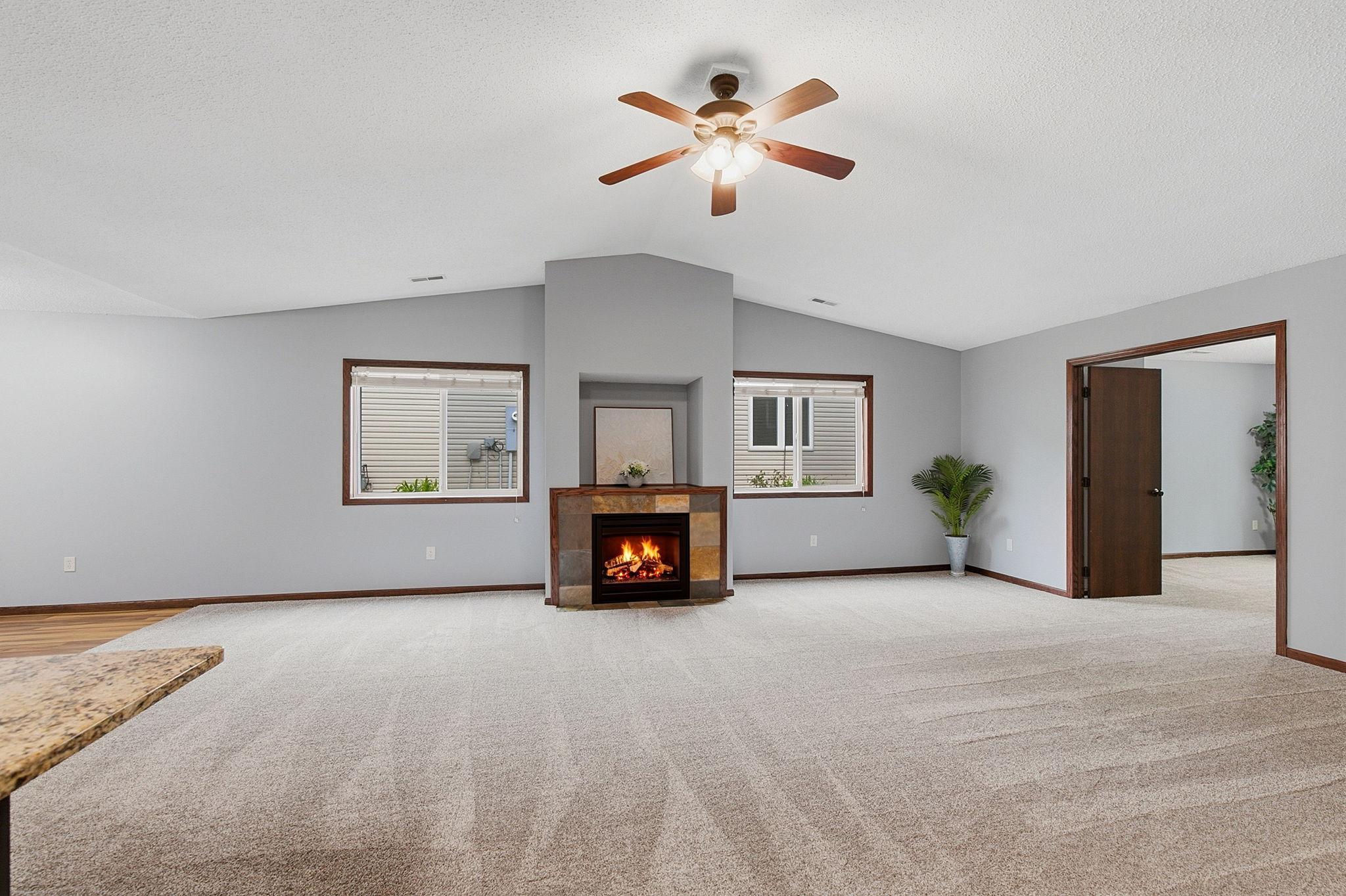 Bright and spacious living room featuring vaulted ceilings, a cozy fireplace, and large windows that fill the space with natural light.