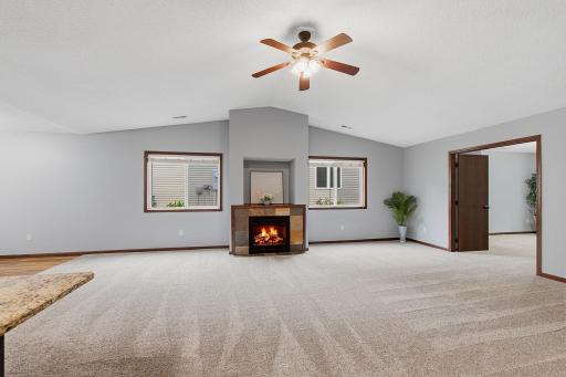 Bright and spacious living room featuring vaulted ceilings, a cozy fireplace, and large windows that fill the space with natural light.