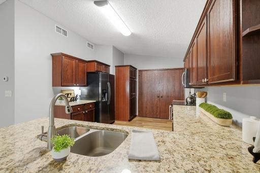 Spacious kitchen with granite countertops, double-basin undermount sink, black appliances, and rich wood cabinetry offering ample storage.