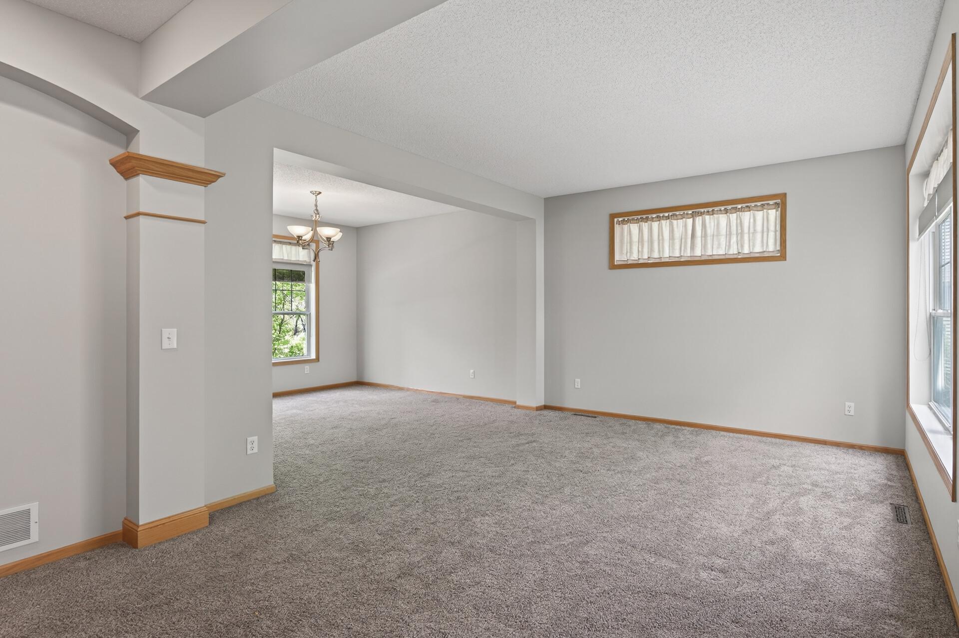 Spacious living room with fresh neutral tones and plush carpeting throughout.