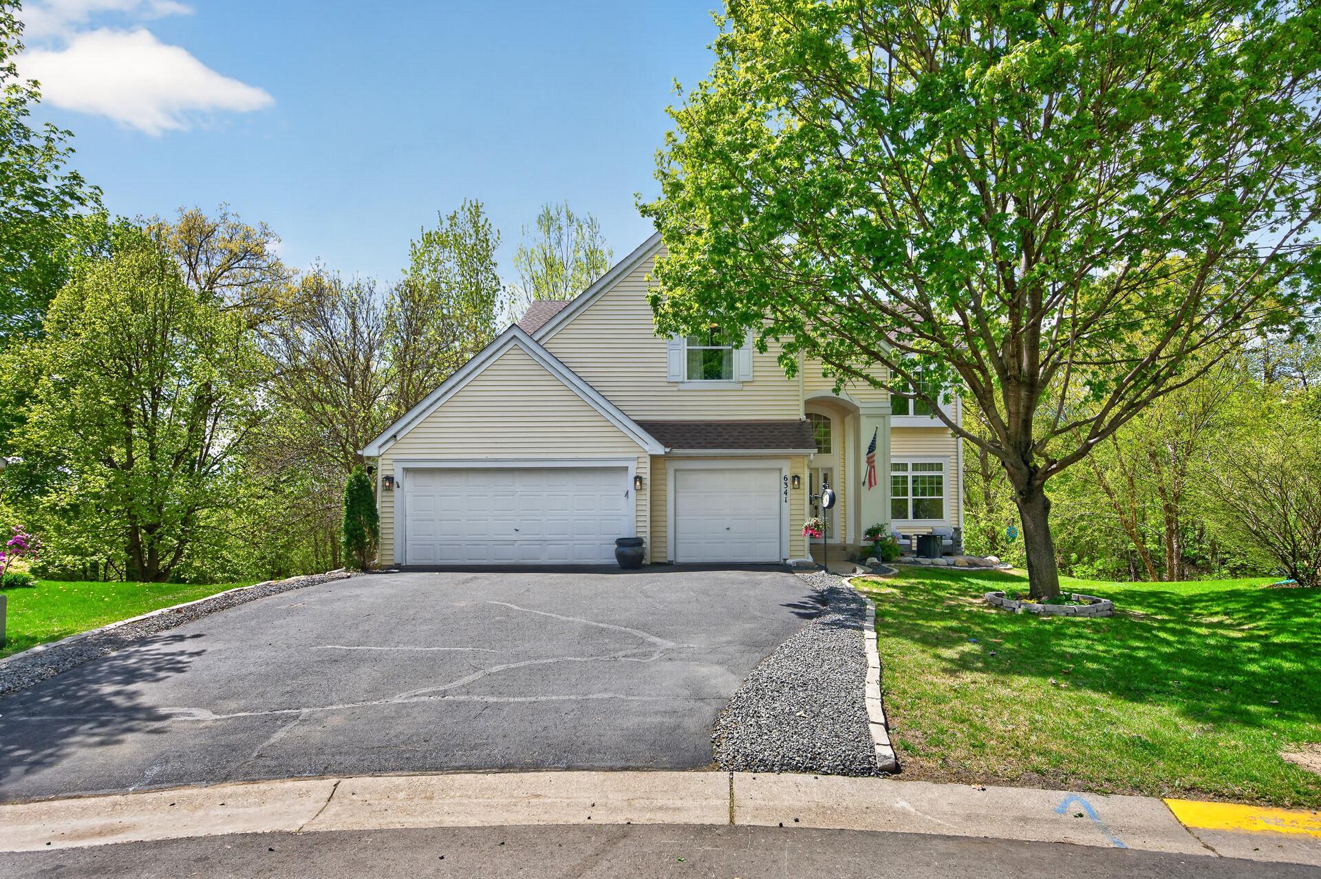 Stunning two-story exterior with mature trees, expansive driveway, and 3-car garage.