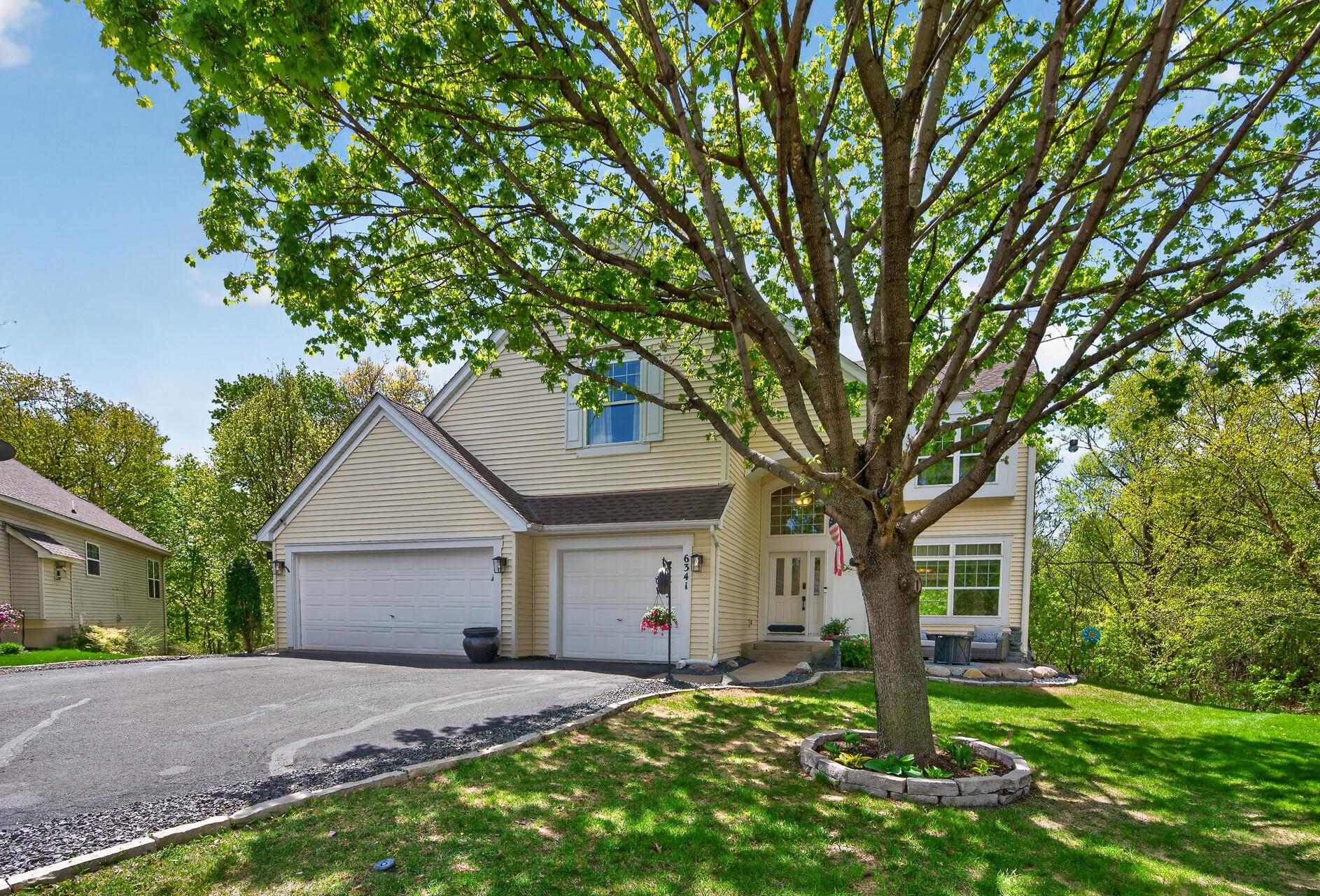 Beautiful curb appeal highlighted by lush landscaping, towering shade tree, and welcoming front entry.