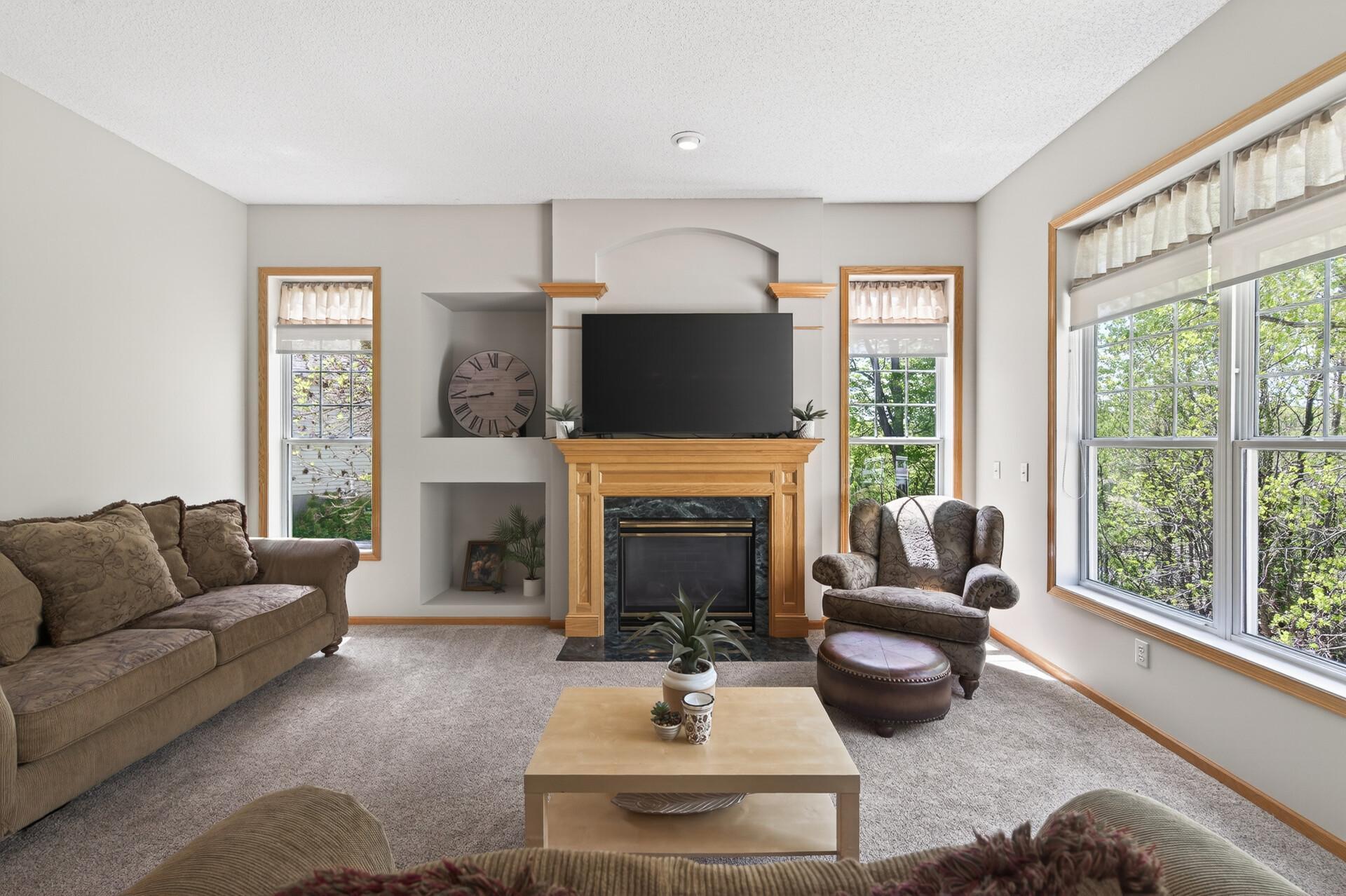 Inviting family room featuring custom built-ins, fireplace surround, and tranquil backyard scenery.