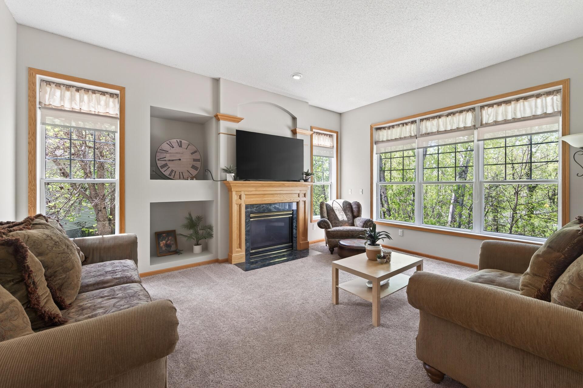 Comfortable family room centered around a cozy gas fireplace and oversized windows with wooded views.