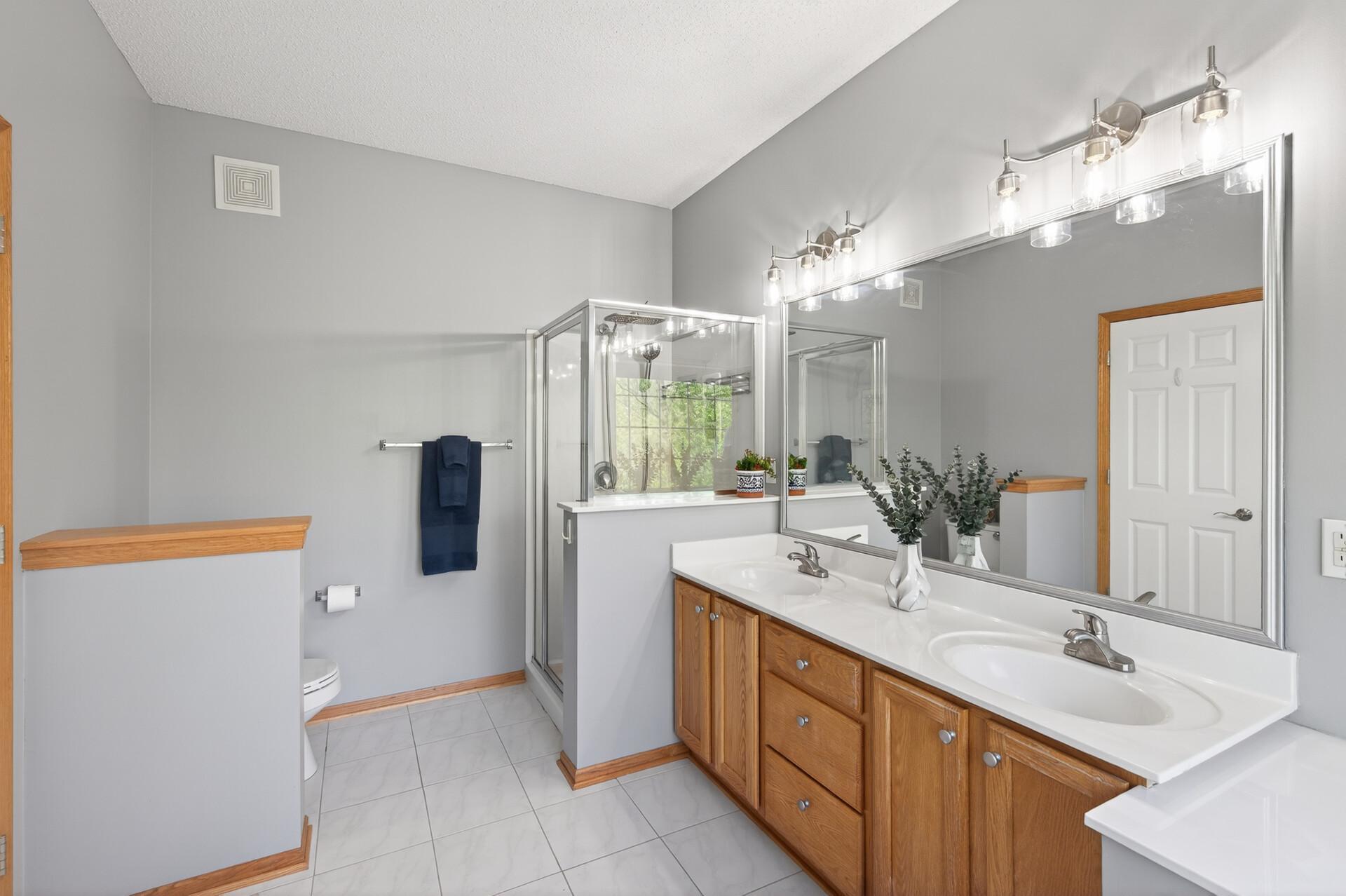 Well-appointed primary bath with separate shower, dual sinks, and ample counter space.