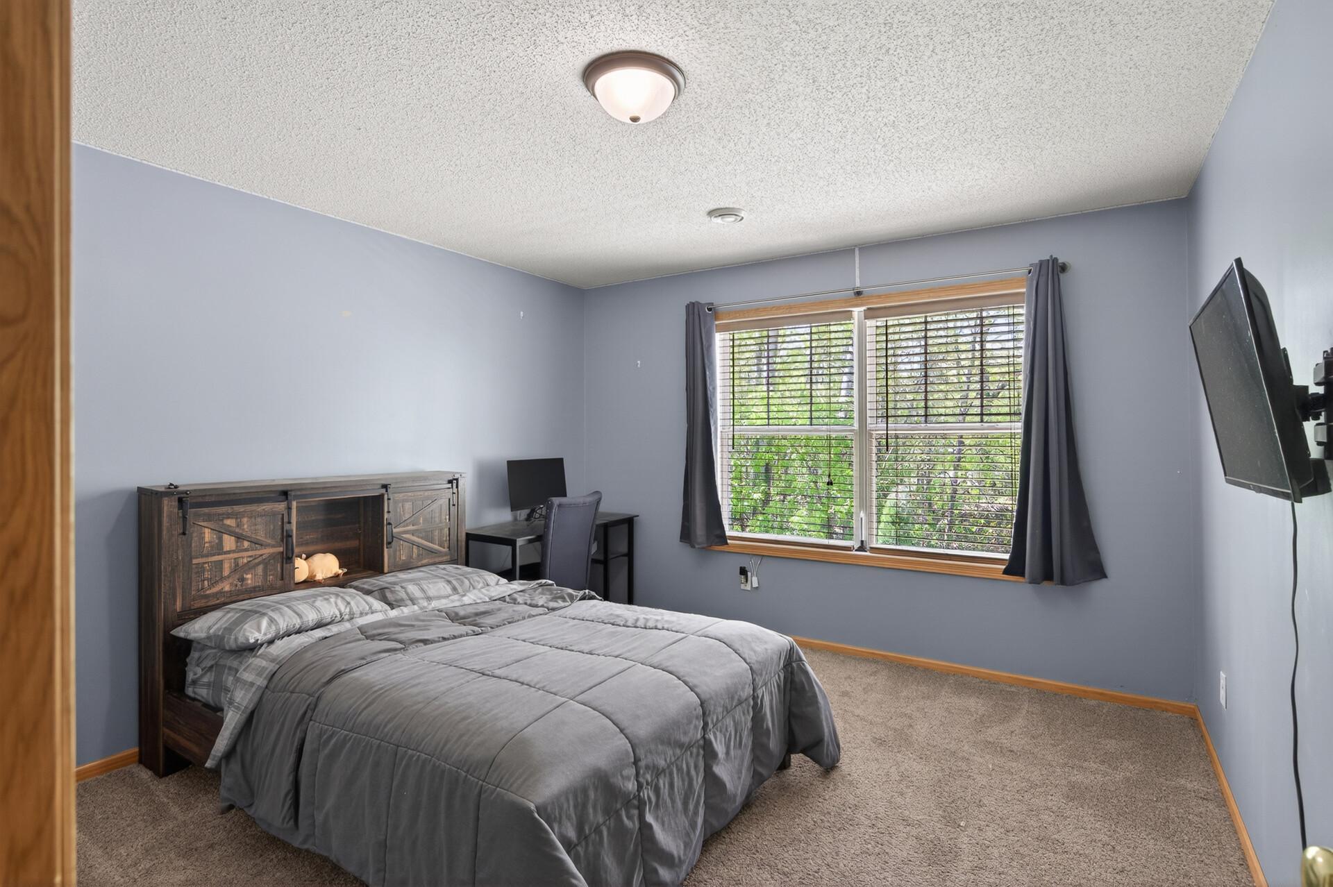 Spacious lower-level bedroom with wooded views, neutral finishes, and flexible layout options.
