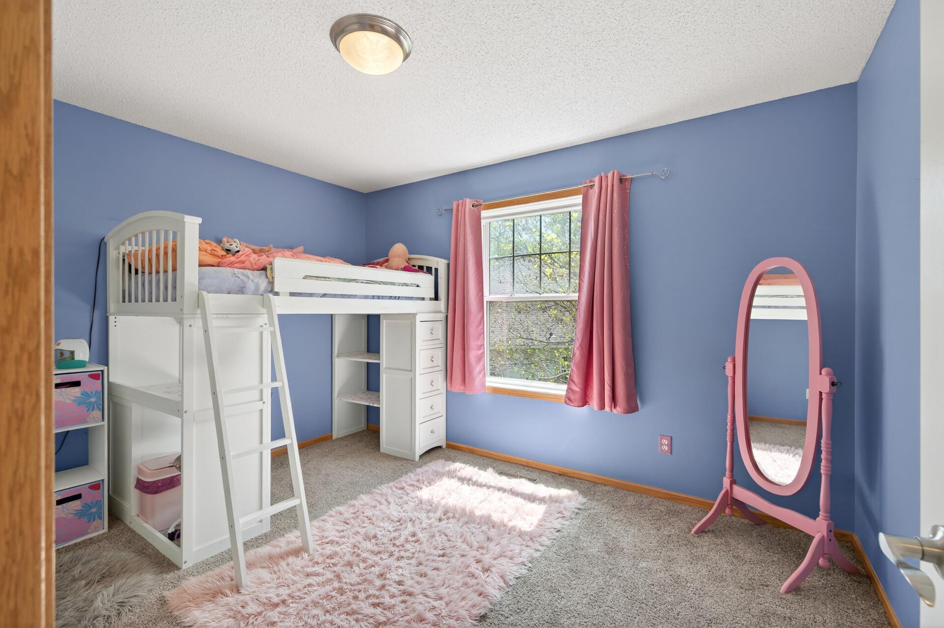 Charming bedroom with whimsical décor, large window, and cozy layout.