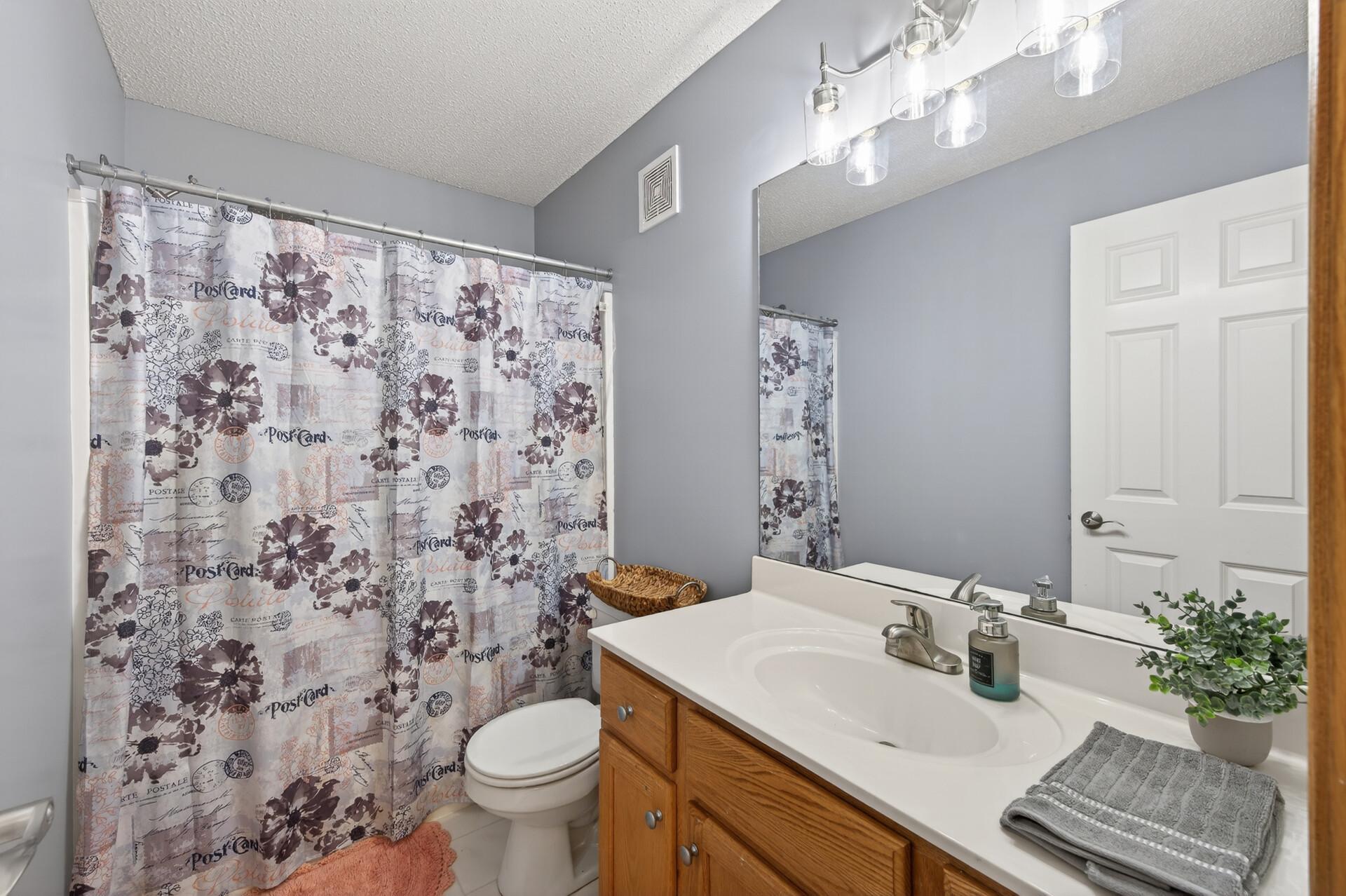Full upper-level bathroom with oversized vanity, updated lighting, and neutral finishes.