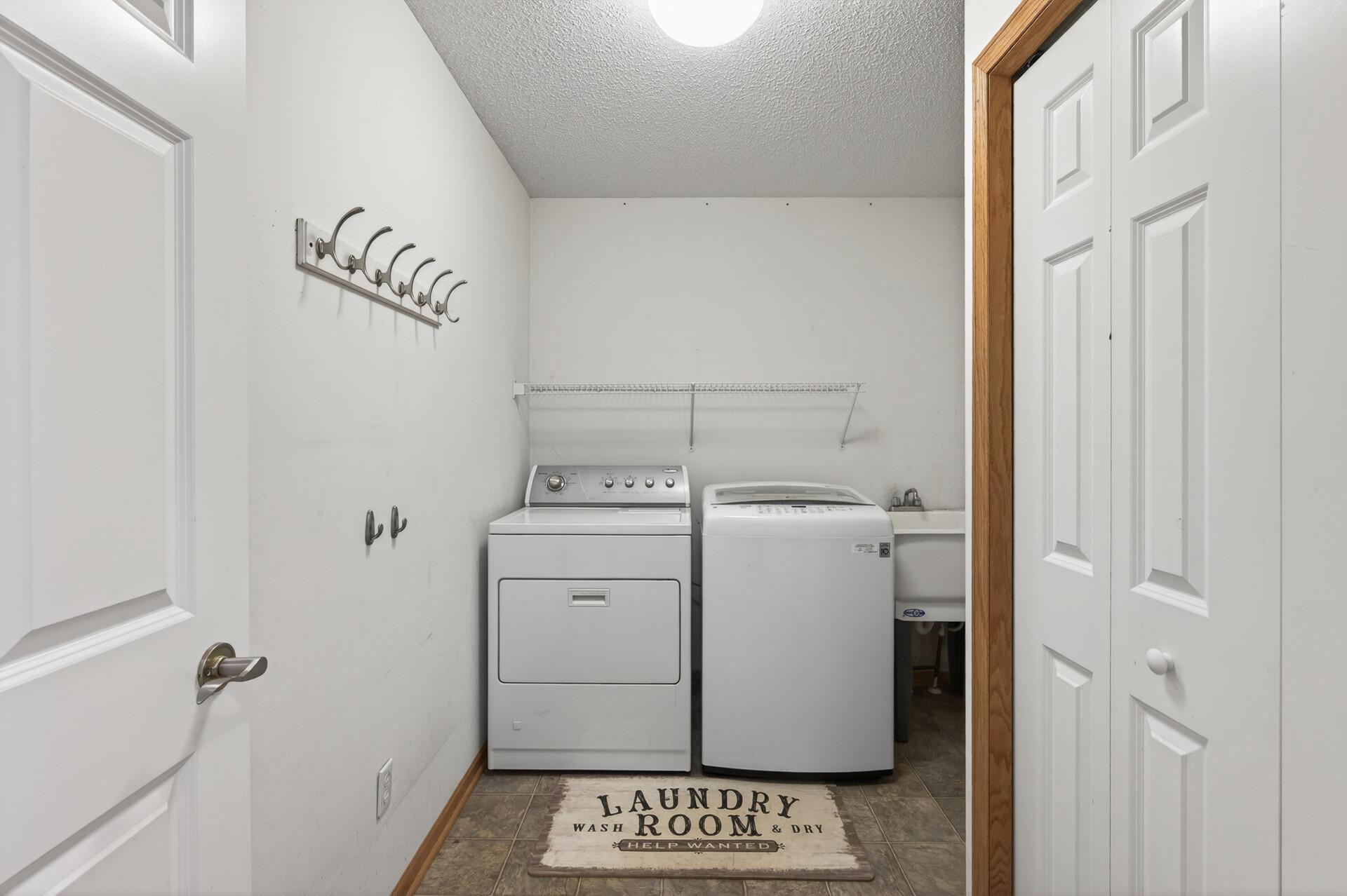 Spacious laundry and utility room with utility sink, storage shelving, and functional workspace.