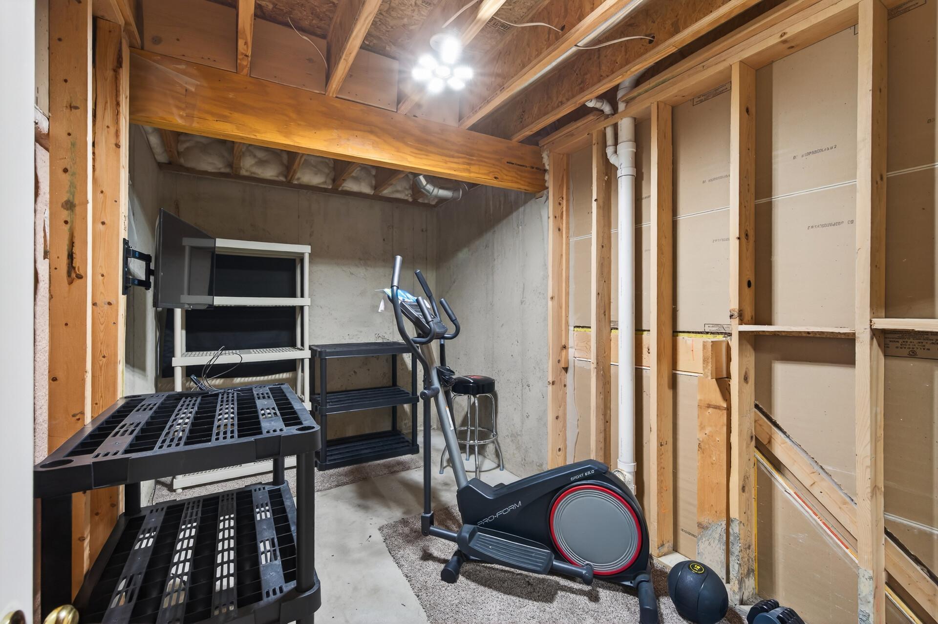 Unfinished storage and workout space offering excellent potential for hobbies, fitness, or additional storage needs.