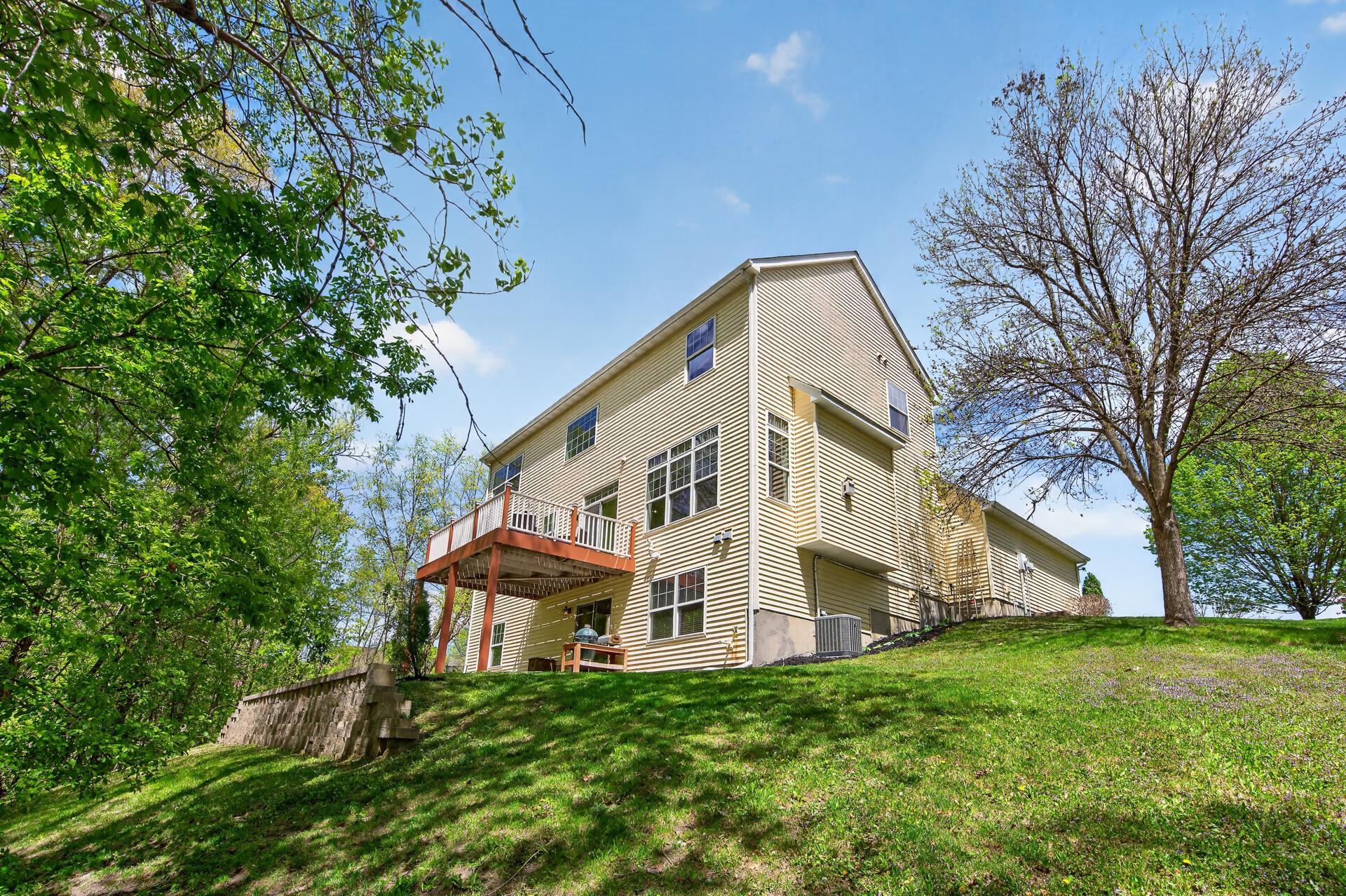 Spacious backyard with elevated deck, mature trees, and picturesque wooded surroundings.
