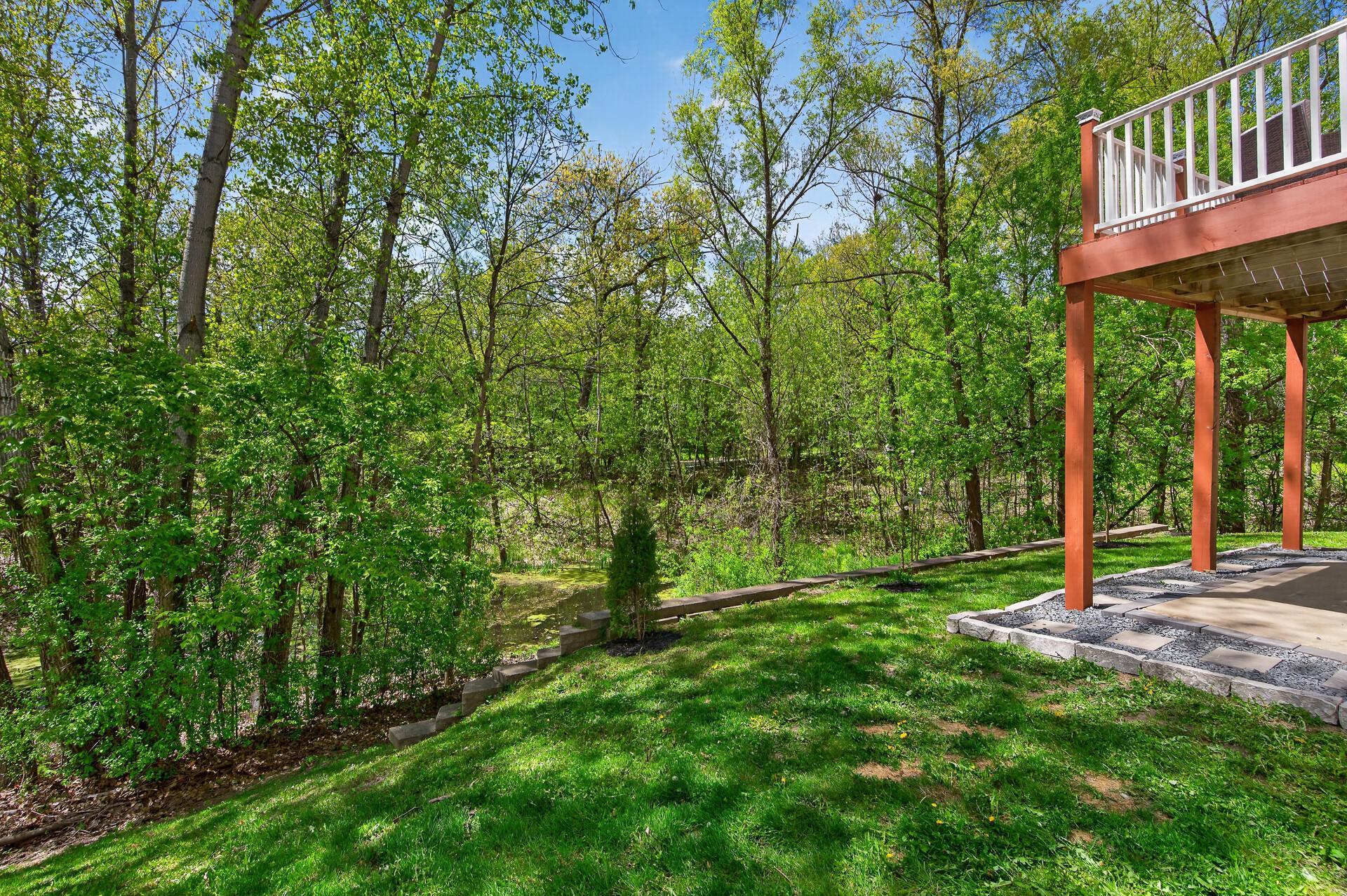 Serene backyard setting with mature trees, terraced landscaping, and private green space.