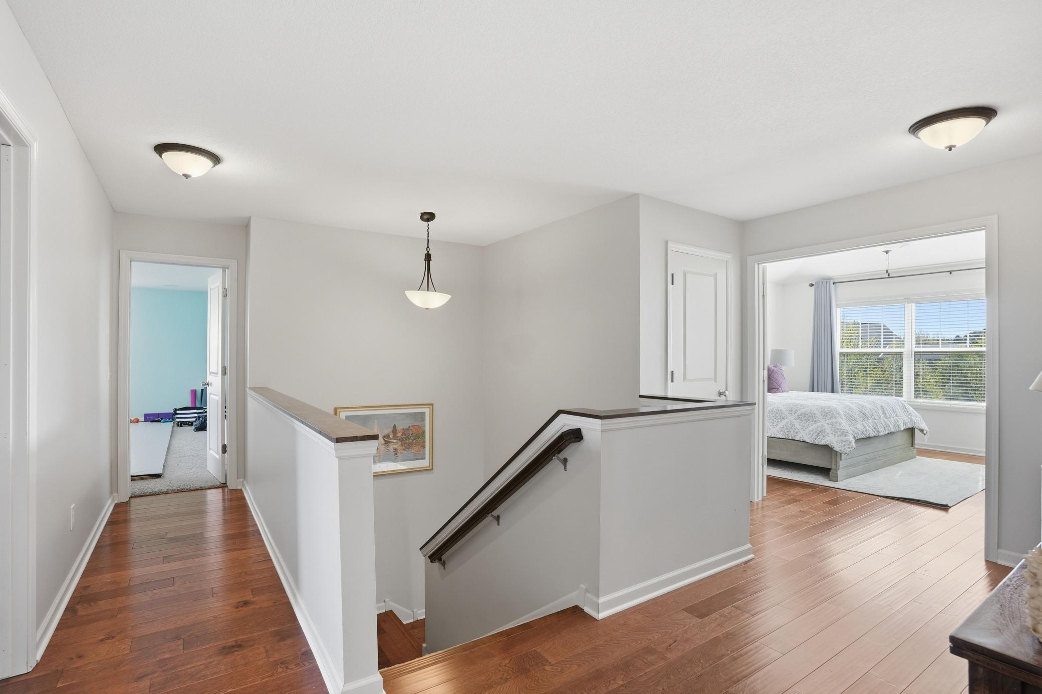 Open upper-level loft with warm hardwood floors and clean, modern lines.