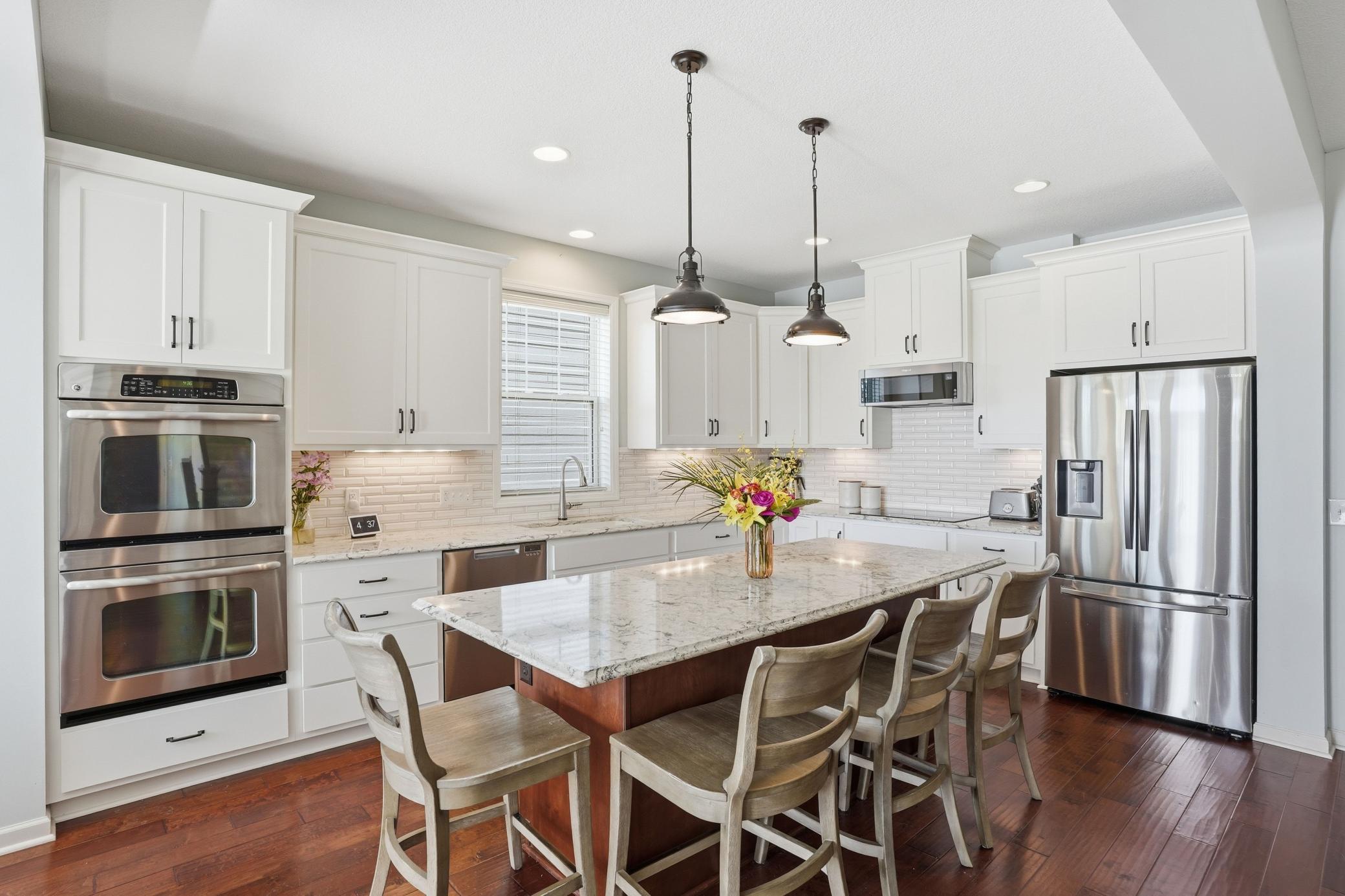 Crisp white cabinetry paired with stainless steel appliances and rich hardwood floors.