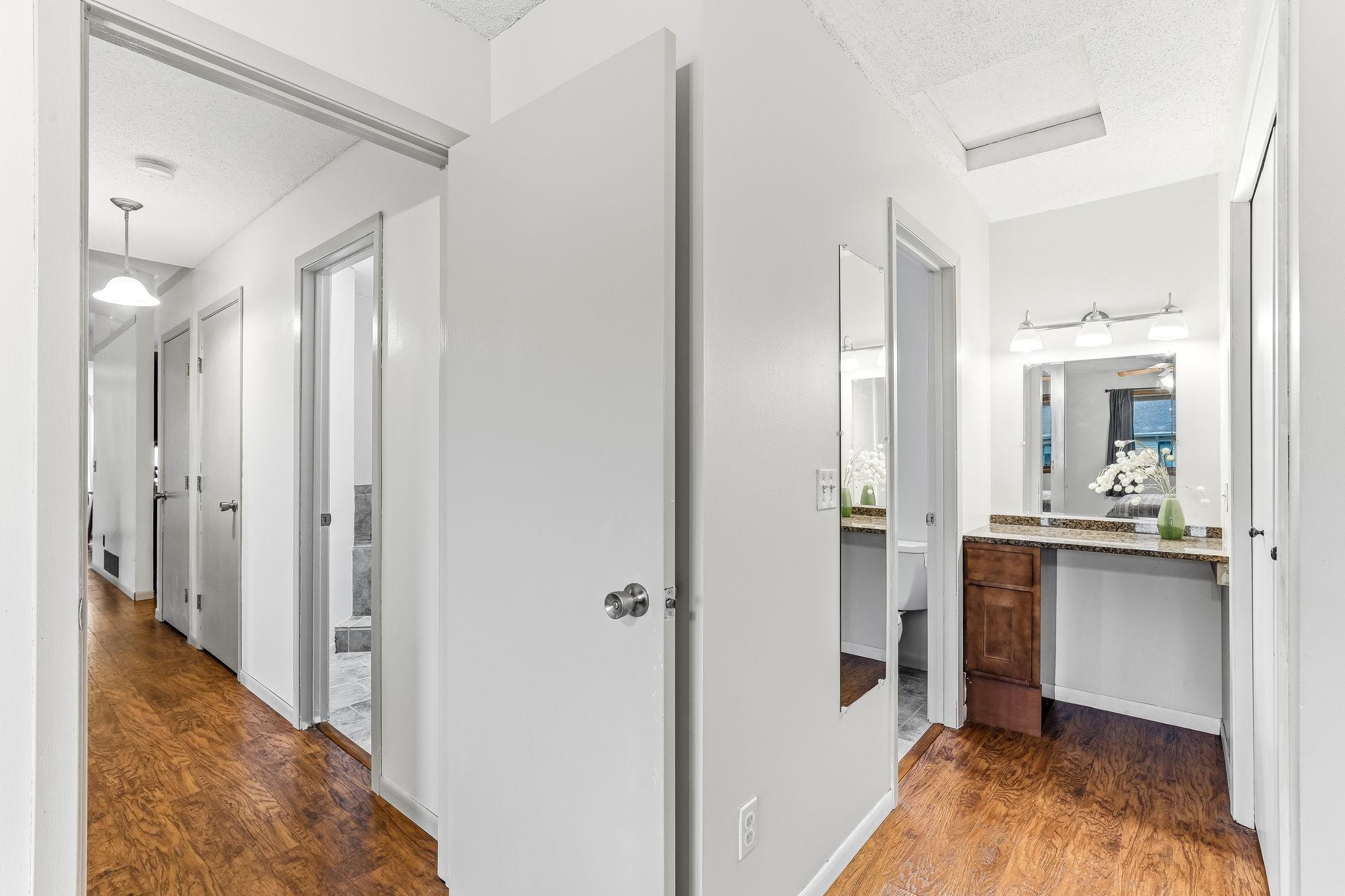 Upper-level hallway connecting the bedrooms and primary suite, featuring durable wood-look flooring, vaulted ceiling details, and a bright open layout throughout the second level.