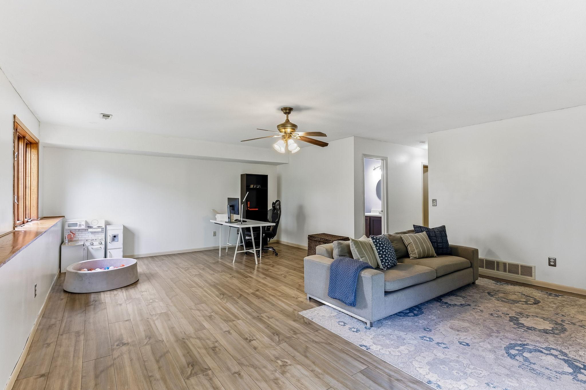 Alternate view of the expansive lower-level living area showcasing the open-concept layout, updated flooring, and multiple options for entertaining, relaxing, or work-from-home functionality.