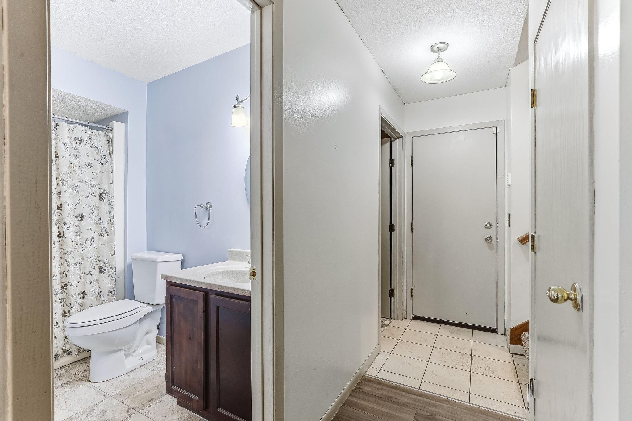 3/4 bathroom conveniently located near the entry and living spaces, complete with vanity, durable tile flooring, and walk-in shower access.