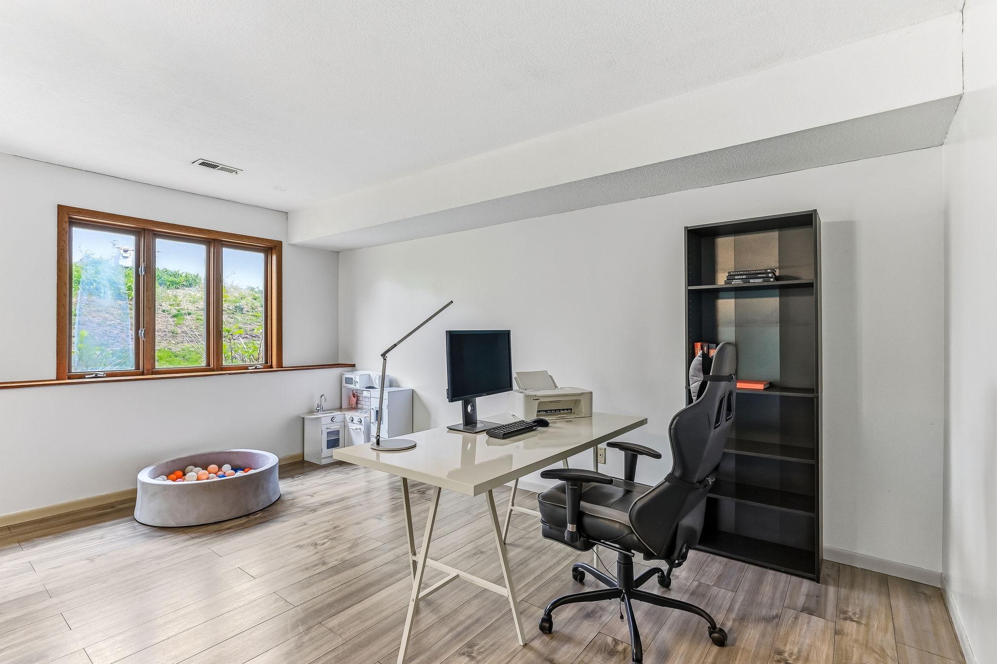 Flexible lower-level bonus space ideal for a home office, workout area, playroom, media space, or secondary living room, complete with durable flooring and lookout windows for natural light.