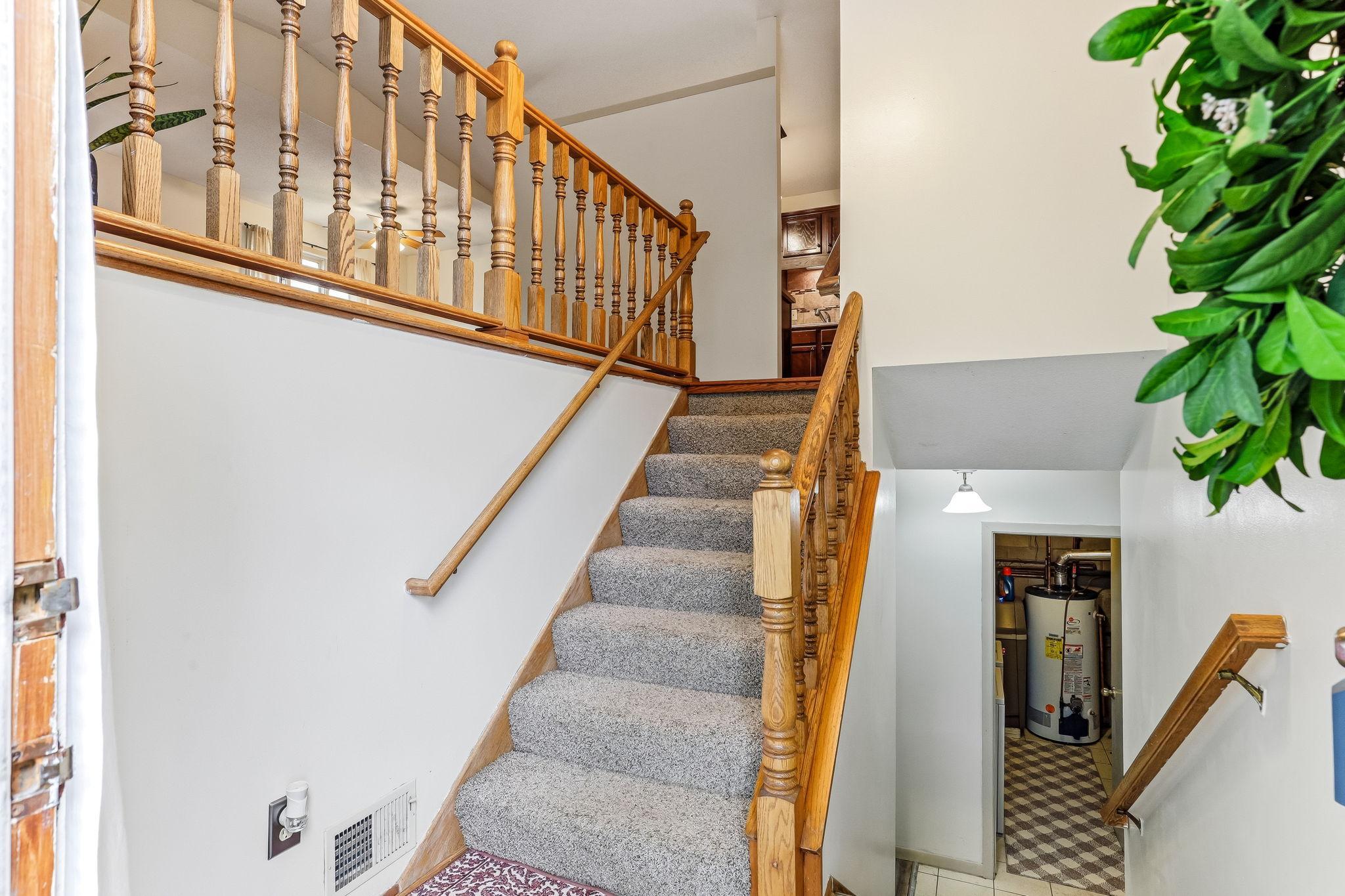 Split-level entryway in this move-in ready Inver Grove Heights townhome featuring updated carpet, natural wood railing, bright interior spaces, and functional access to upper living areas and finished lower-level flex space.