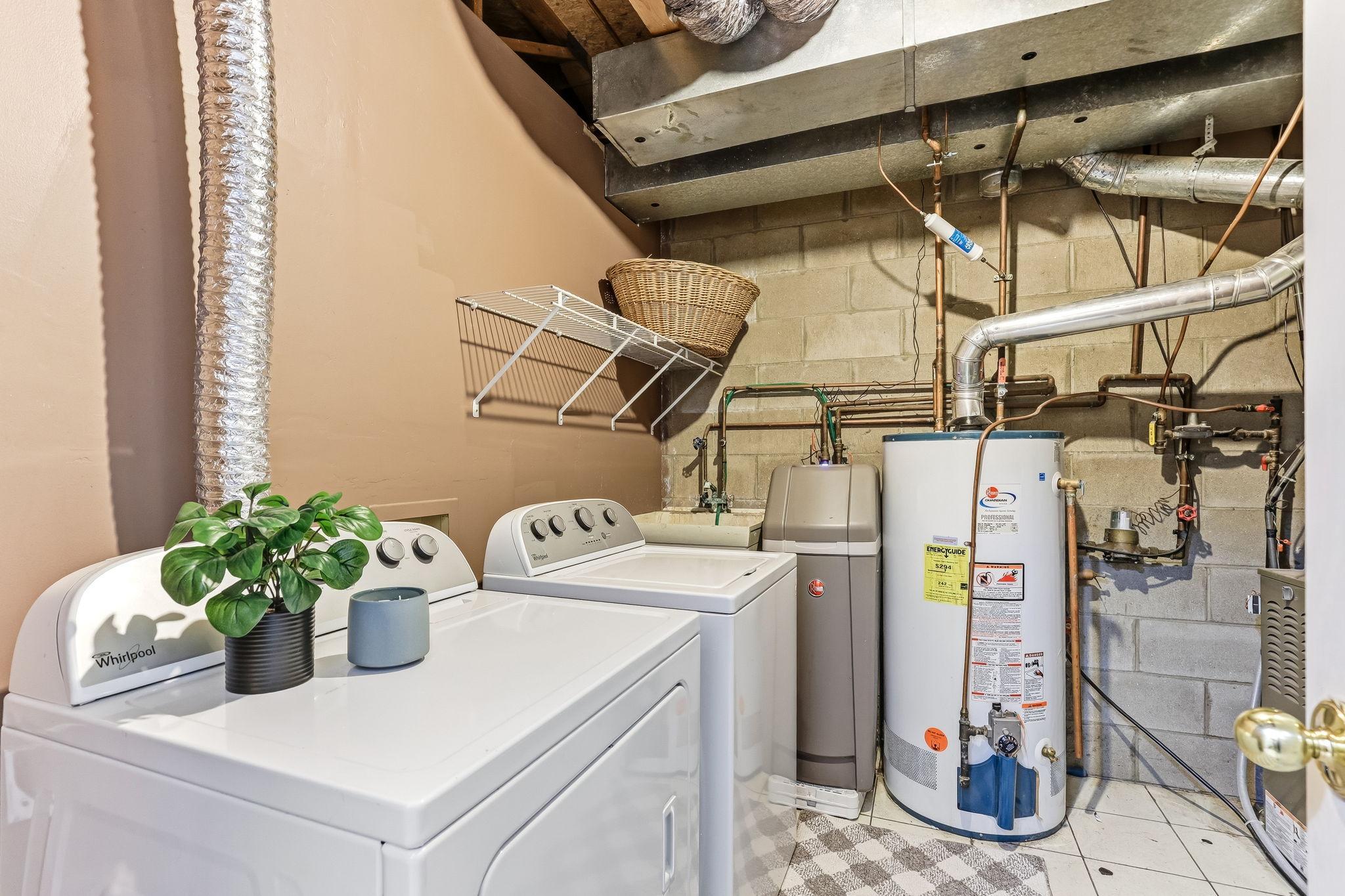 Dedicated laundry and utility space with washer and dryer setup, additional storage shelving, and easy access to major mechanical systems.
