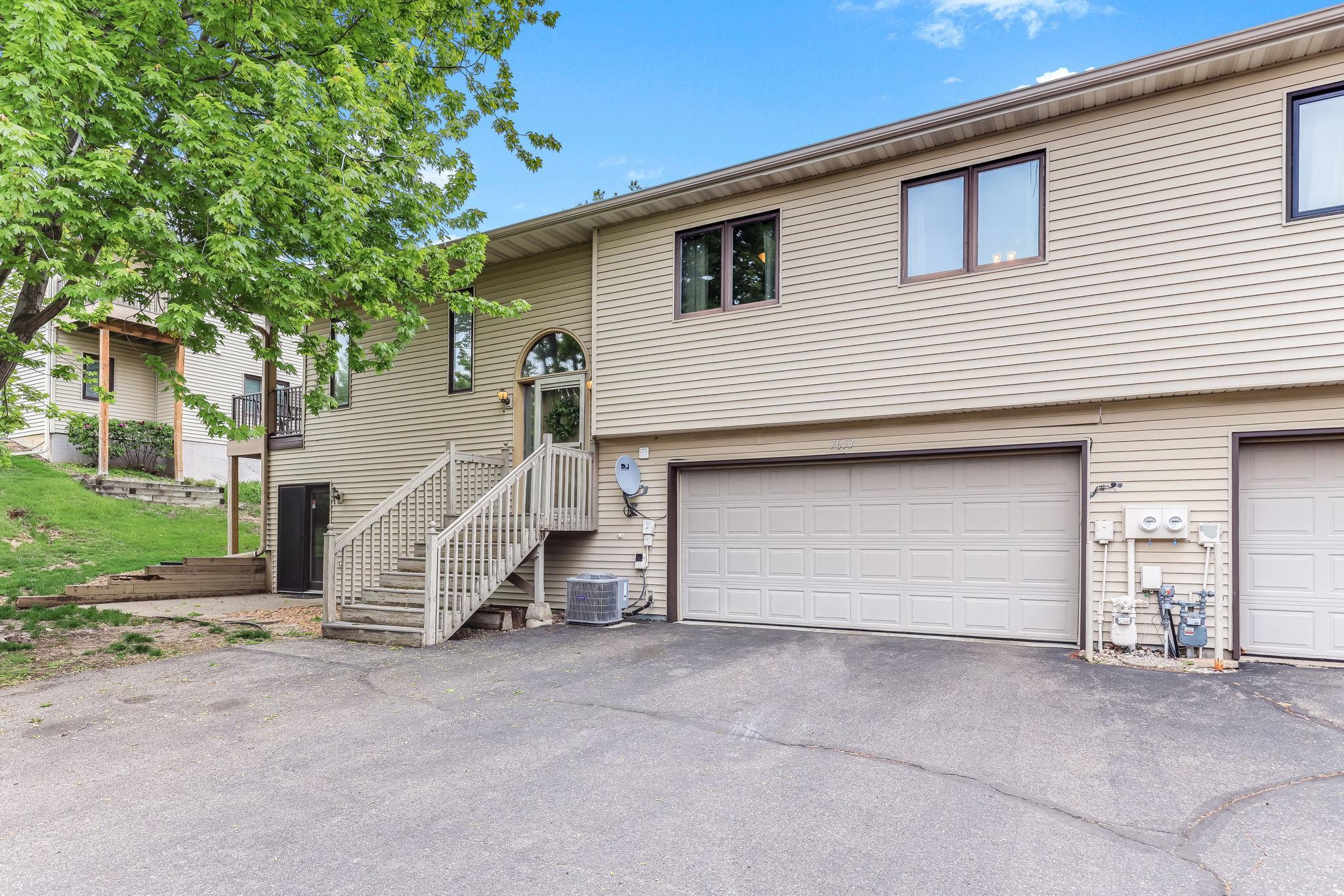 Exterior view of 7653 Borman Way in Inver Grove Heights showcasing low-maintenance townhome living with attached garage, mature trees, updated exterior paint, and convenient access to parks, shopping, highways, and St. Paul.