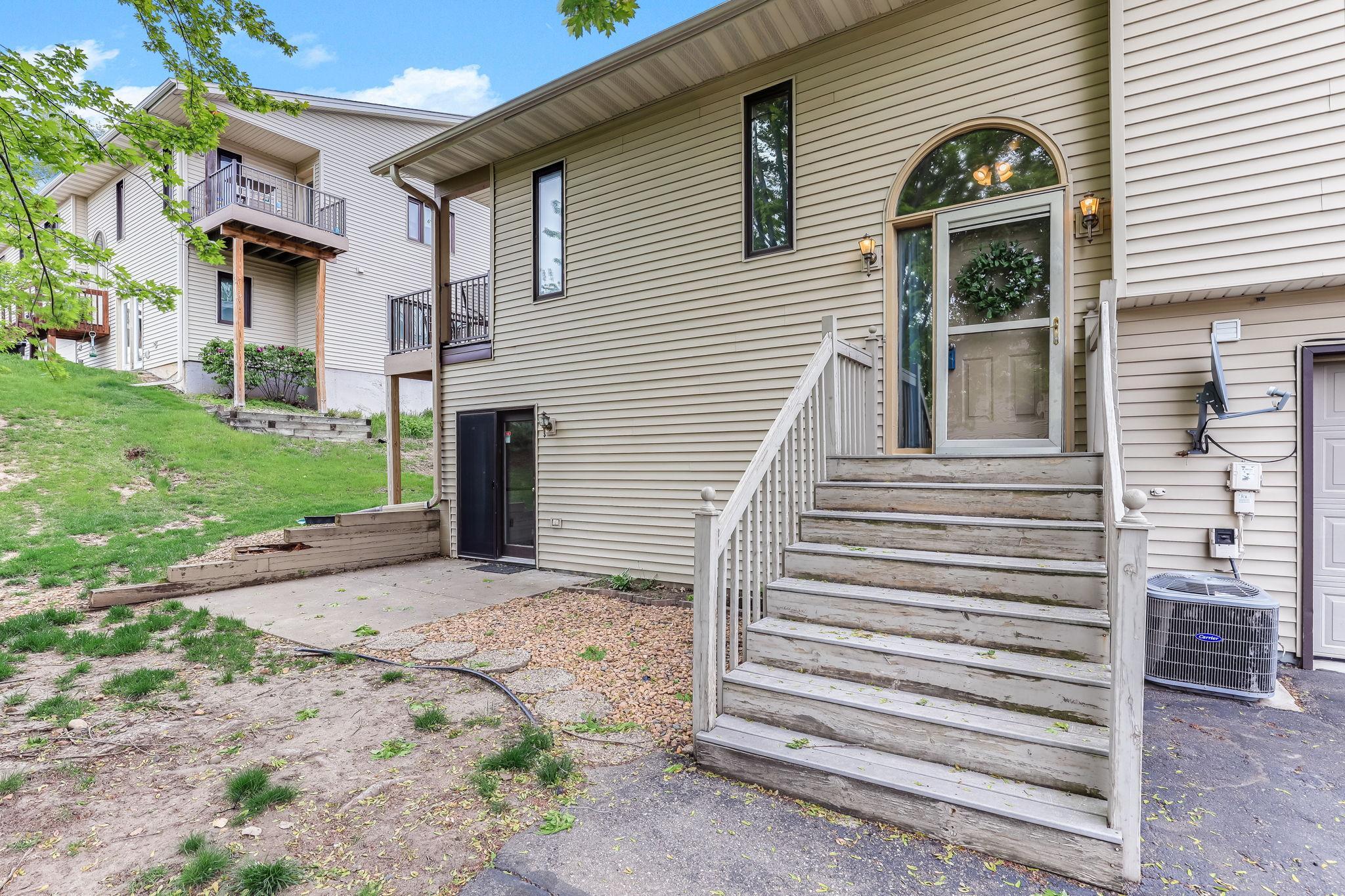 Welcoming front entrance at 7653 Borman Way featuring elevated entry stairs, mature trees, private townhome setting, and low-maintenance HOA living in a convenient Inver Grove Heights location near St. Paul and Twin Cities amenities.