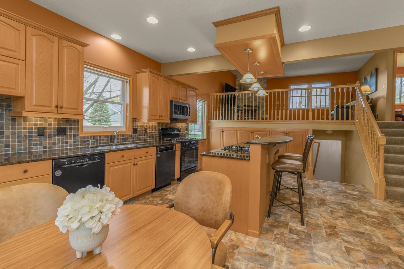 Recessed lighting, soaring ceilings, and sleek granite counters give this kitchen a timeless feel.