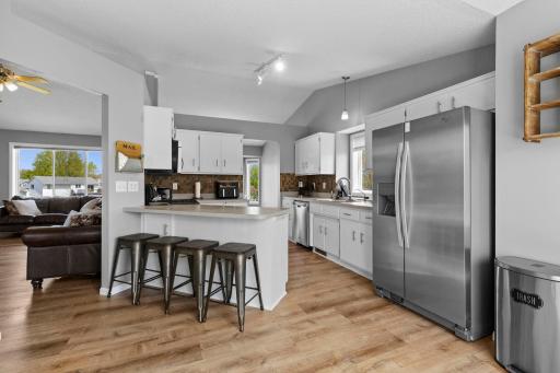 Wonderful white kitchen offers counter seating, stainless appliances and tile backsplash