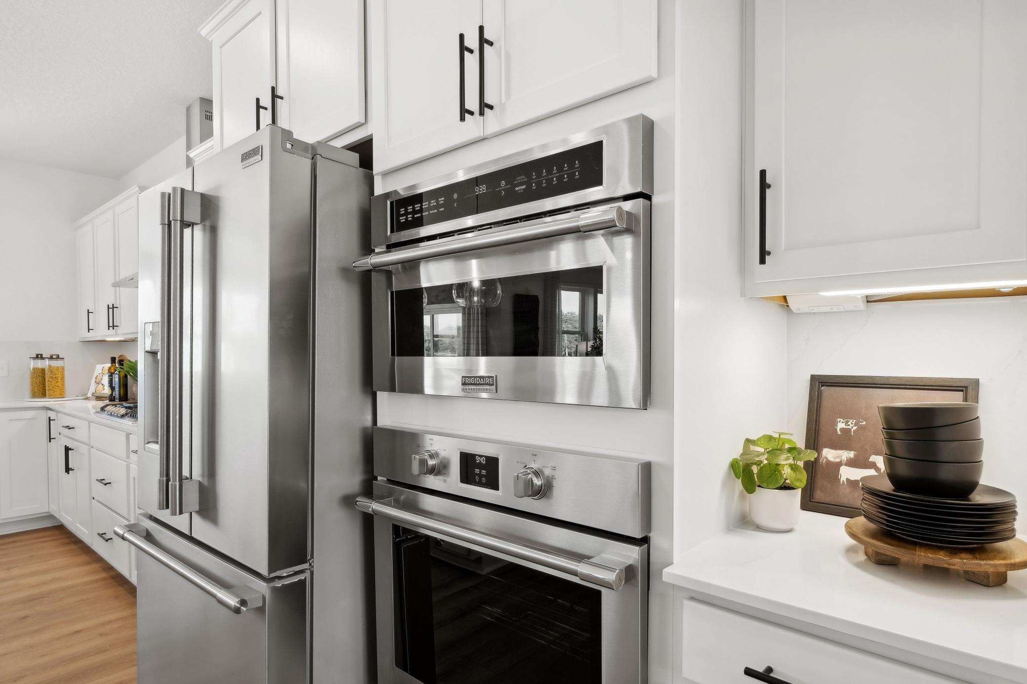 (Photo of a decorated model, actual homes finishes will vary) This stunning gourmet kitchen features a large center island, quartz countertops, LVP floors, stainless appliances and more!