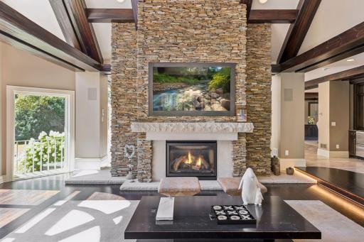 A dramatic living room showcasing soaring vaulted ceilings, expansive windows, and a stunning hand-laid slate fireplace surround