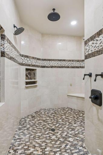 Walk-in shower with 3 shower heads and bench seating