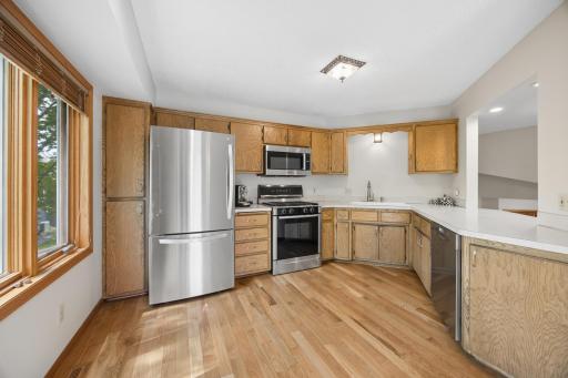 The kitchen features abundant cabinetry, stainless steel appliances, and sun-filled windows.