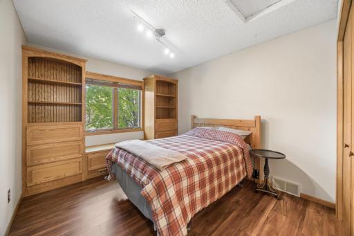 Charming secondary bedroom with custom built-ins, warm wood accents, and a cozy nook for reading by the window.