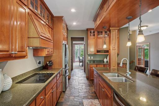Stone countertops, stainless steel appliances, glass-front cabinetry, and abundant storage blend luxury with functionality. Chef's kitchen offering an abundance of cabinetry and walk-through butler's pantry to formal dining space.