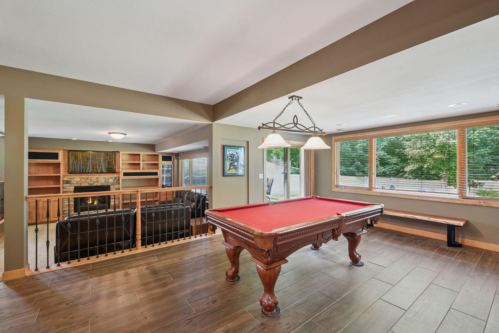 The spacious recreation area features a custom wet bar with extensive space, built-in wine storage, beverage refrigerator, and beautiful wood cabinetry accented by large windows and natural light.