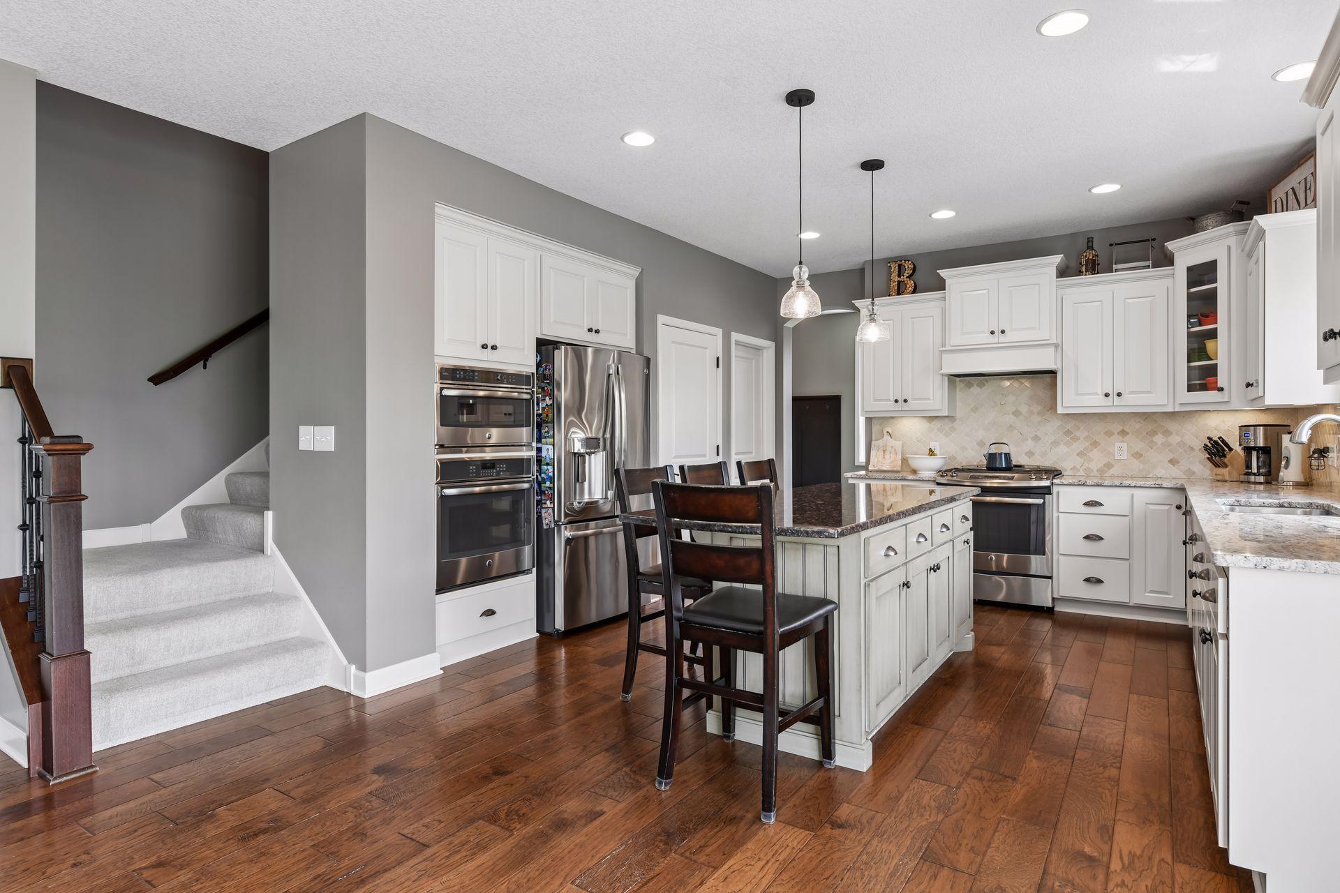Gorgeous chef’s kitchen features abundant cabinetry, generous counter space, center island seating, double ovens, custom tile backsplash, and a gas range.