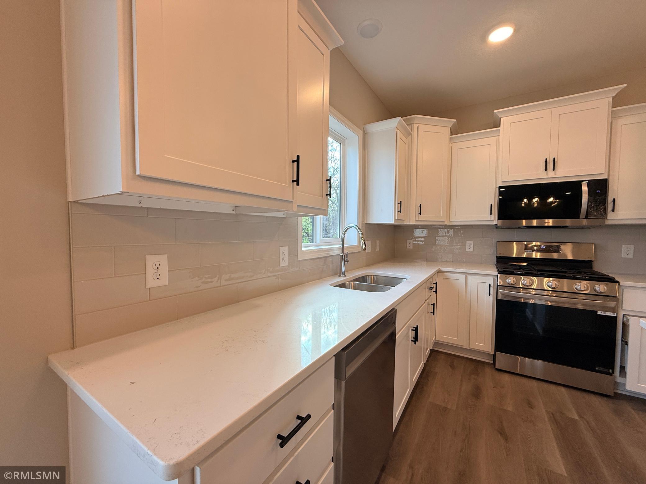 Beautifully light quartz countertops and ceramic tile backsplash make this the perfect backdrop for any color decor