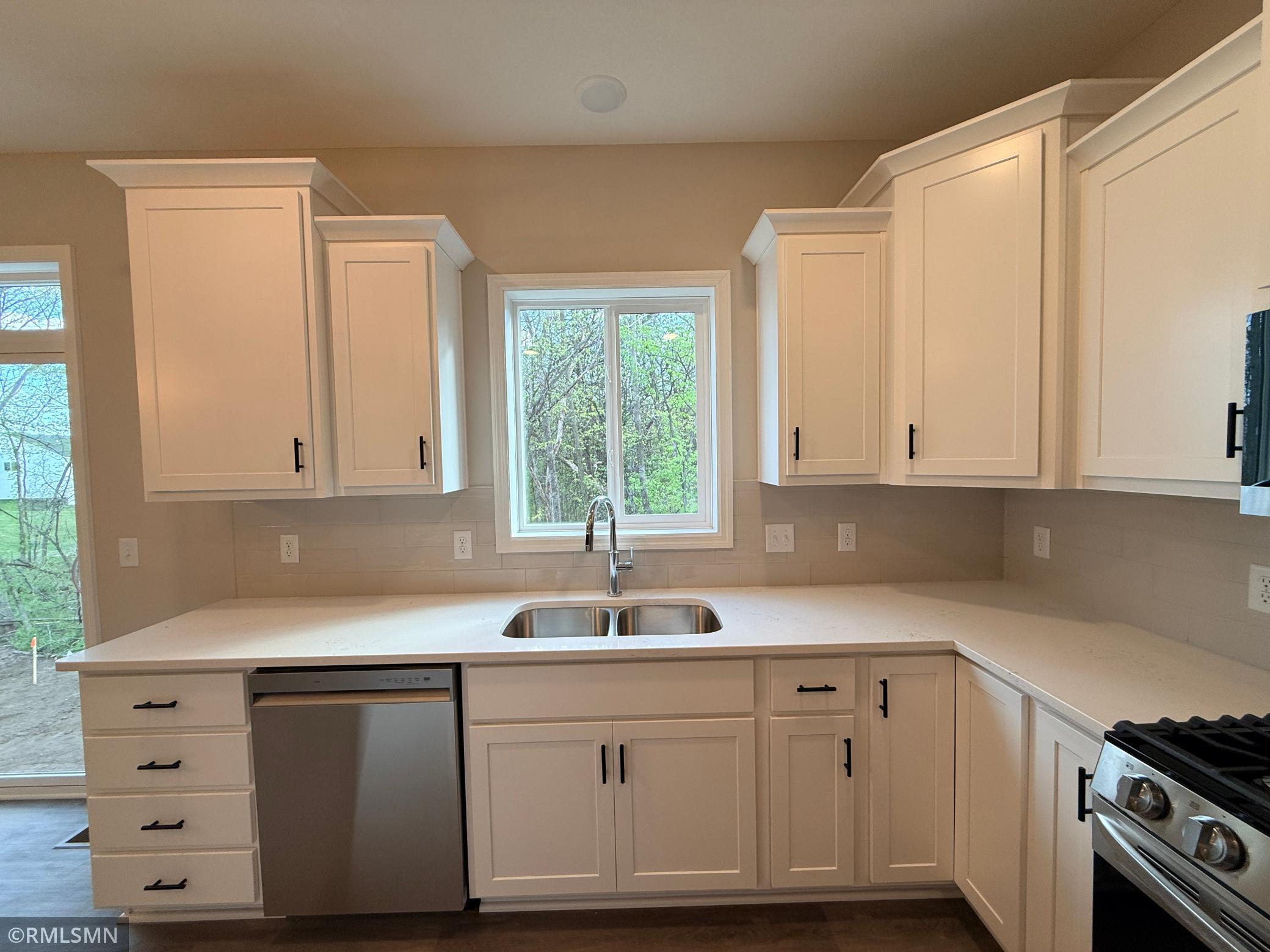 Beautifully light quartz countertops and ceramic tile backsplash make this the perfect backdrop for any color decor
