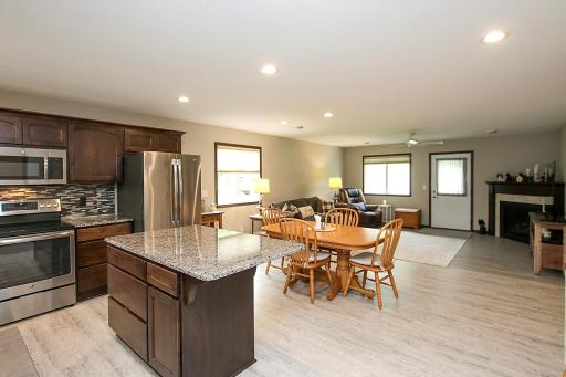 Enter the home through the front door and be welcomed by open concept living with the flowing kitchen, dining and living room areas. The kitchen features dark wood cabinetry, granite countertops and a glass tile backsplash.