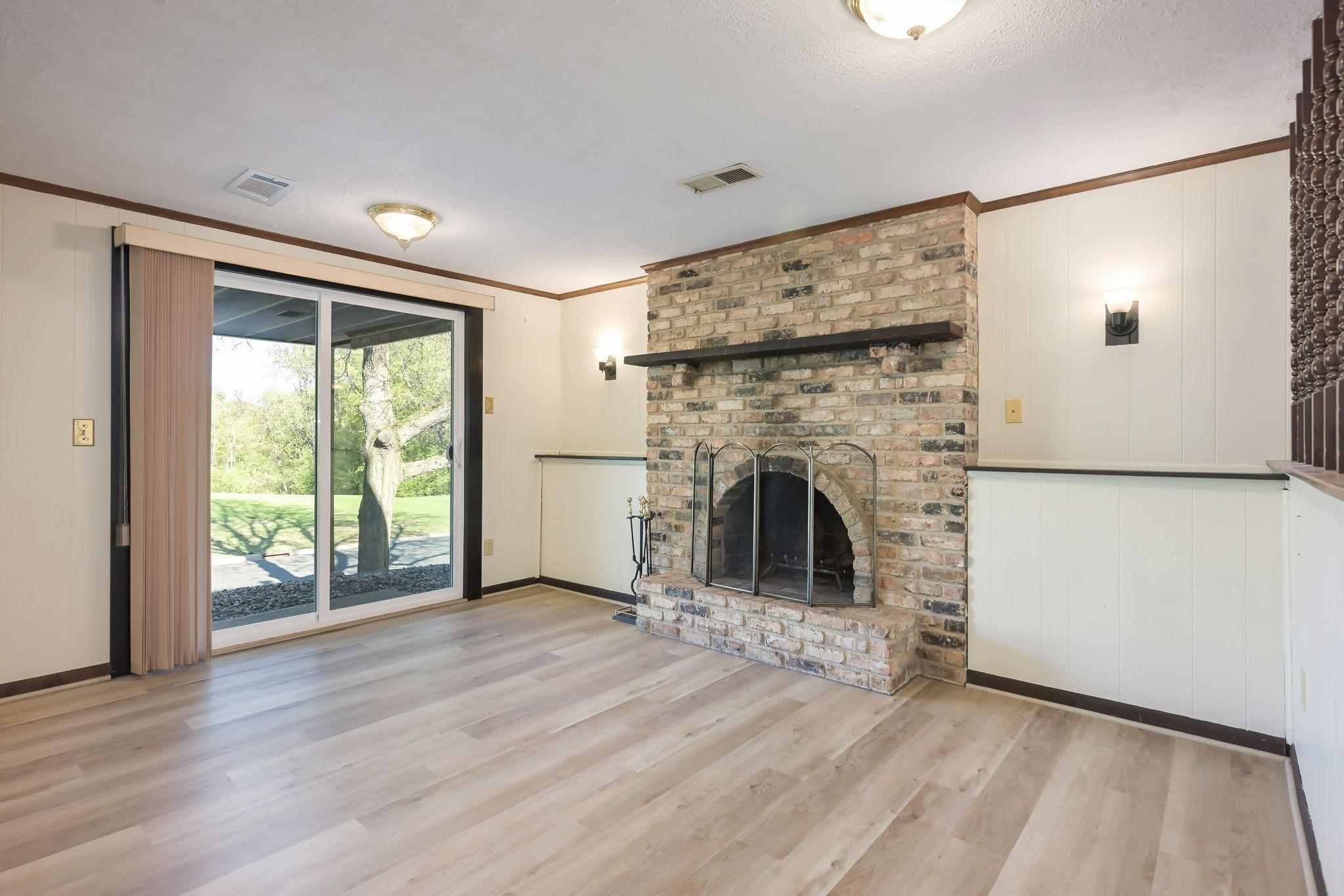 Lower level family room features brick wood burning fireplace and new sliding door!