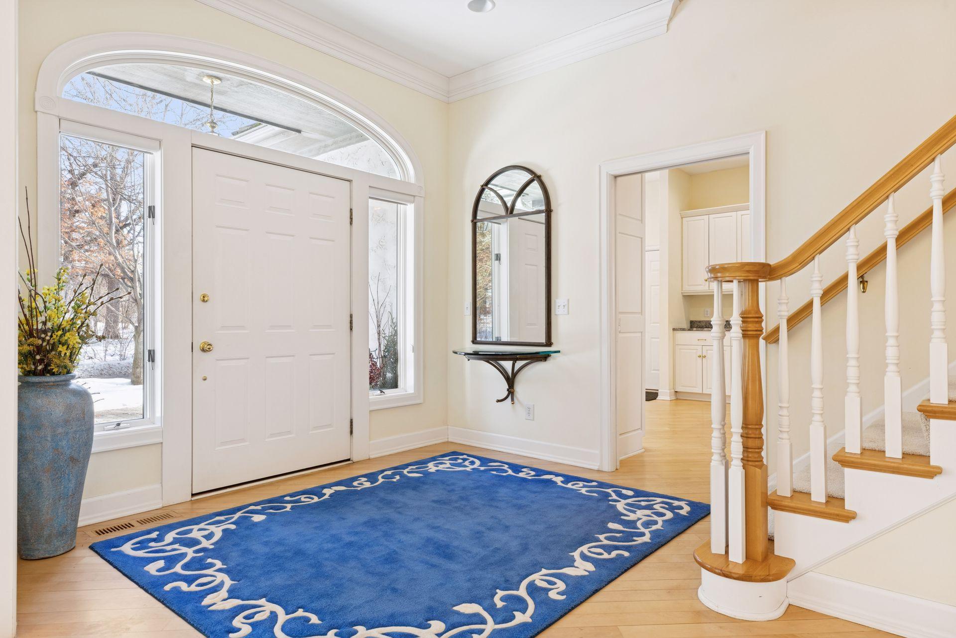 The foyer creates a welcoming arrival with an oversized front door framed by sidelights and a transom window that fills the space with natural light and sets the tone for the scale and quality found throughout the home