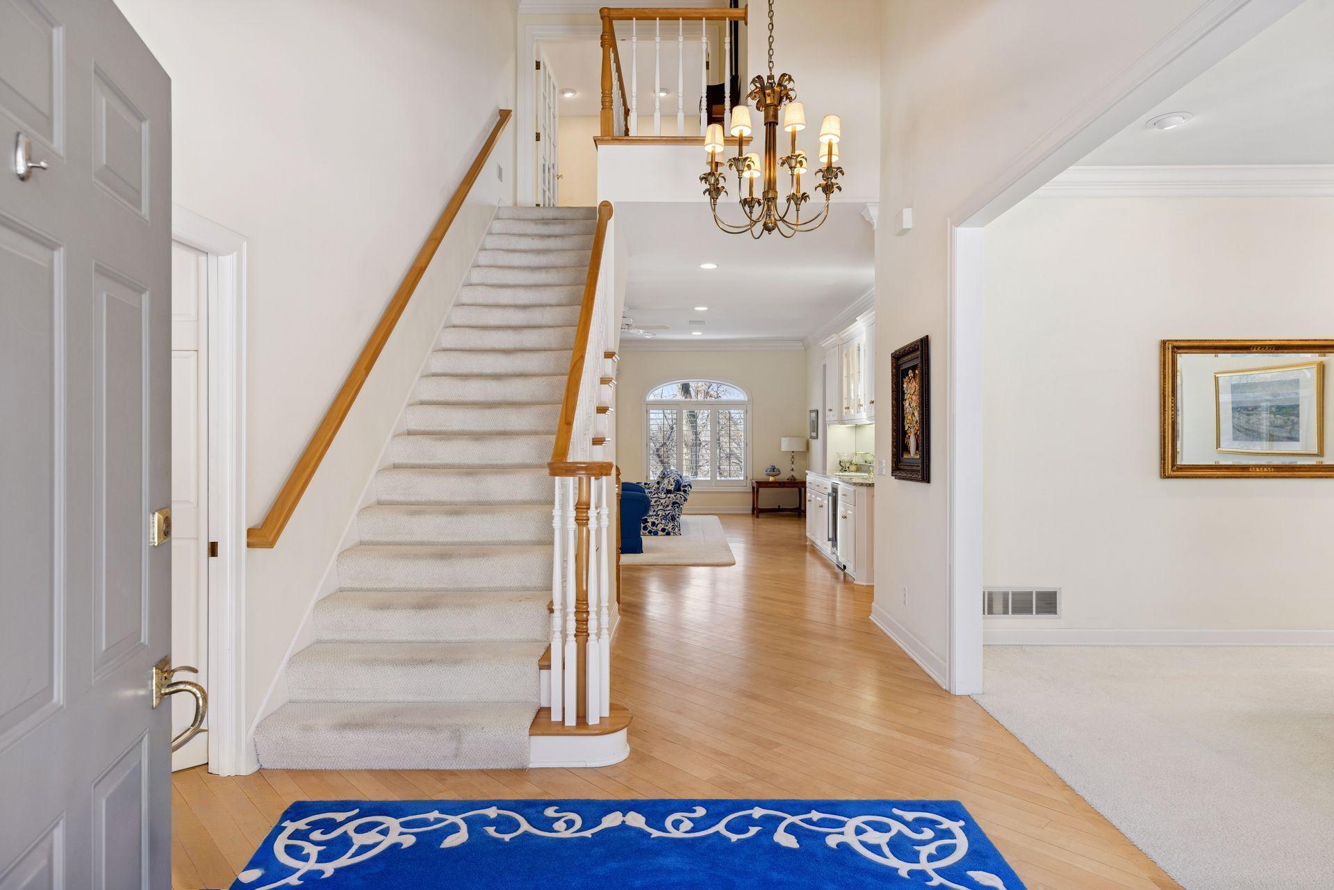 The two-story foyer makes a grand first impression, showcasing an open staircase leading to the private primary suite level, with a glimpse into the inviting living room beyond