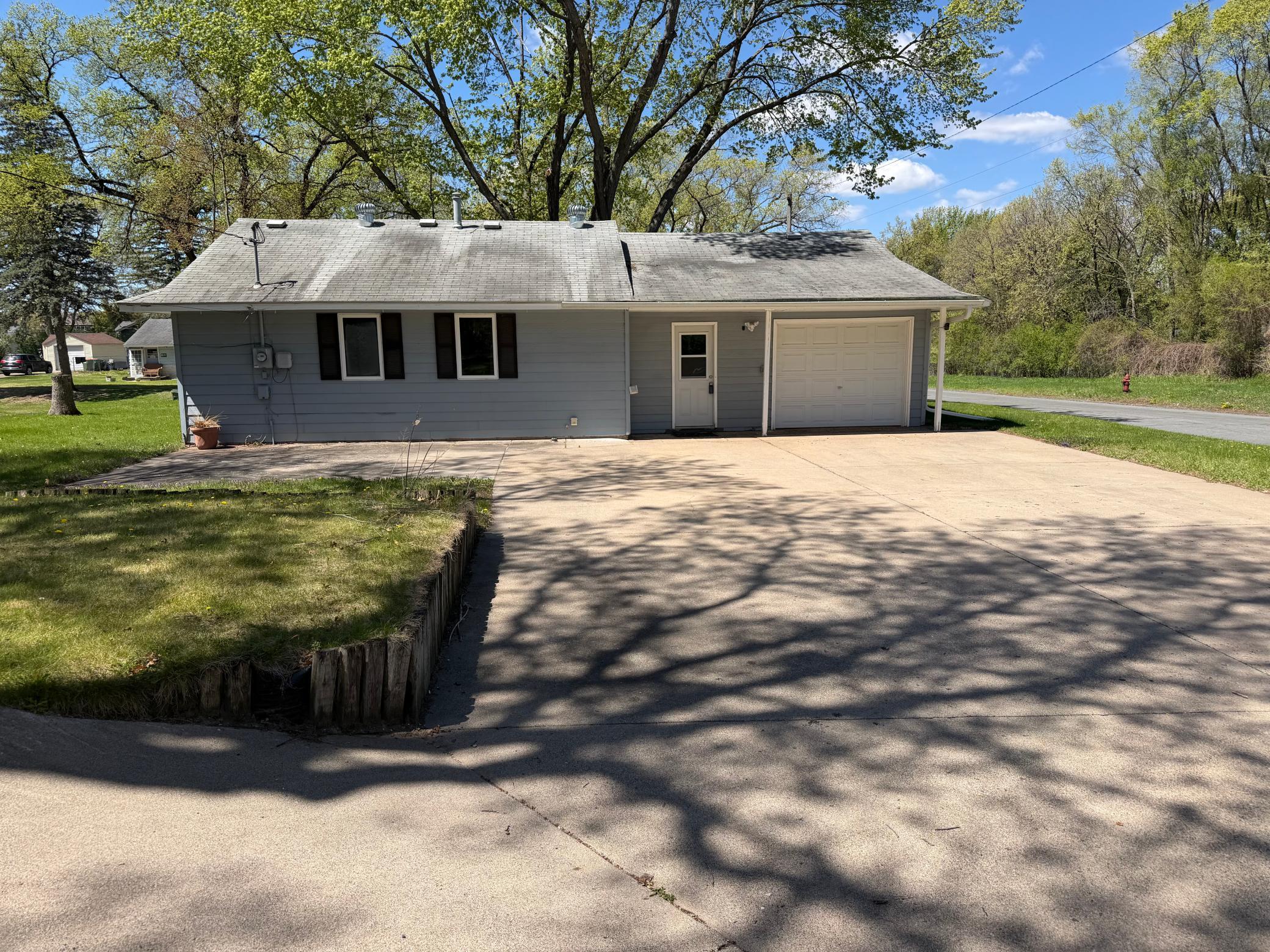 Back of home with attached one car garage and large concrete driveway