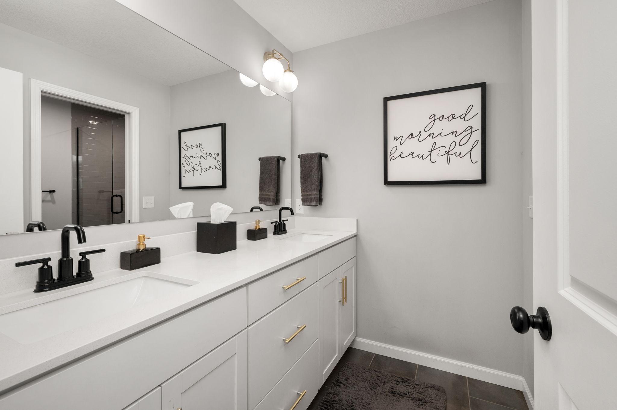 A luxurious Owner’s Suite with a walk-in shower with custom tile/glass door, double vanity, and a spacious walk-in closet