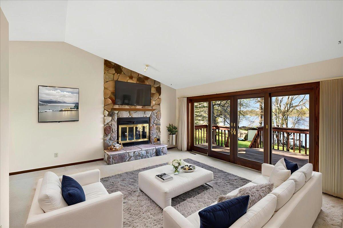 Virtually staged living room showcasing the spacious layout, fireplace, and stunning lake views.