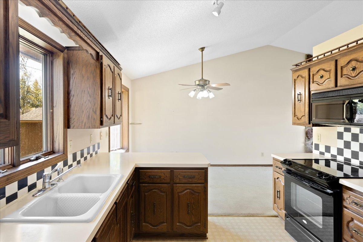 Functional kitchen and dining area with abundant cabinet space, vaulted ceiling, and natural light.
