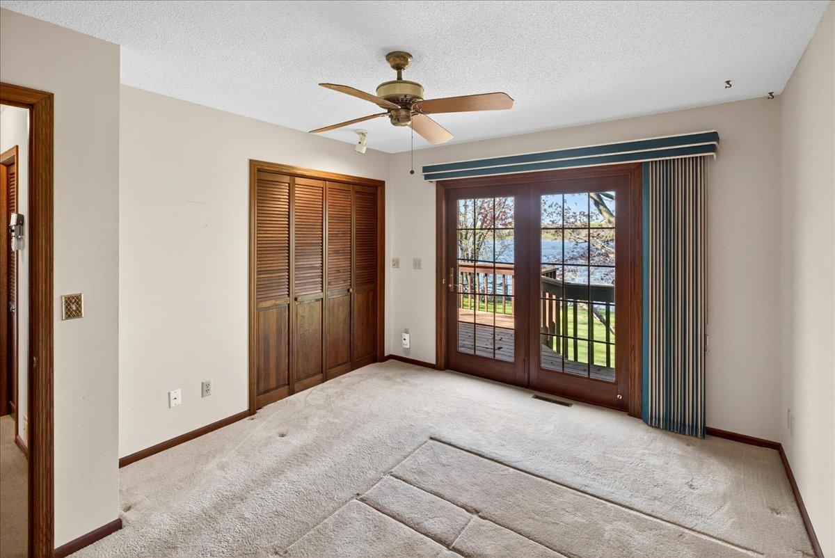 Primary lakeside bedroom with gorgeous lake view and patio door to the deck.