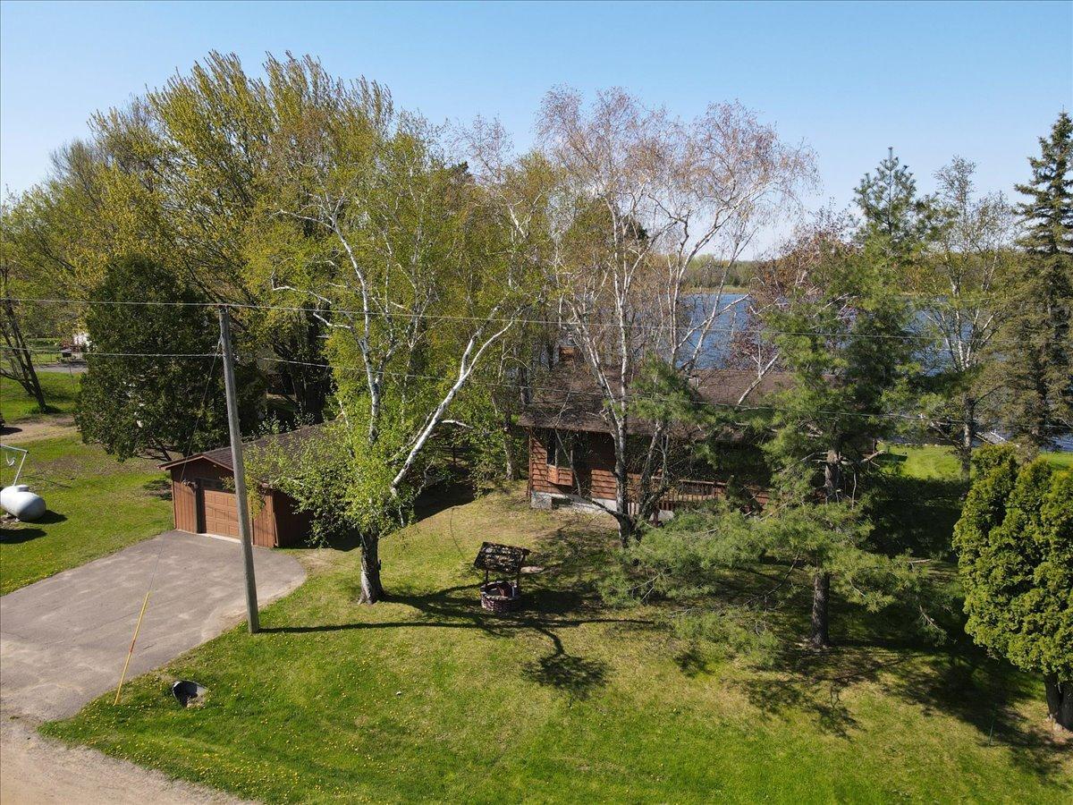 Aerial view highlighting the home, detached garage space, and scenic lakeside surroundings.