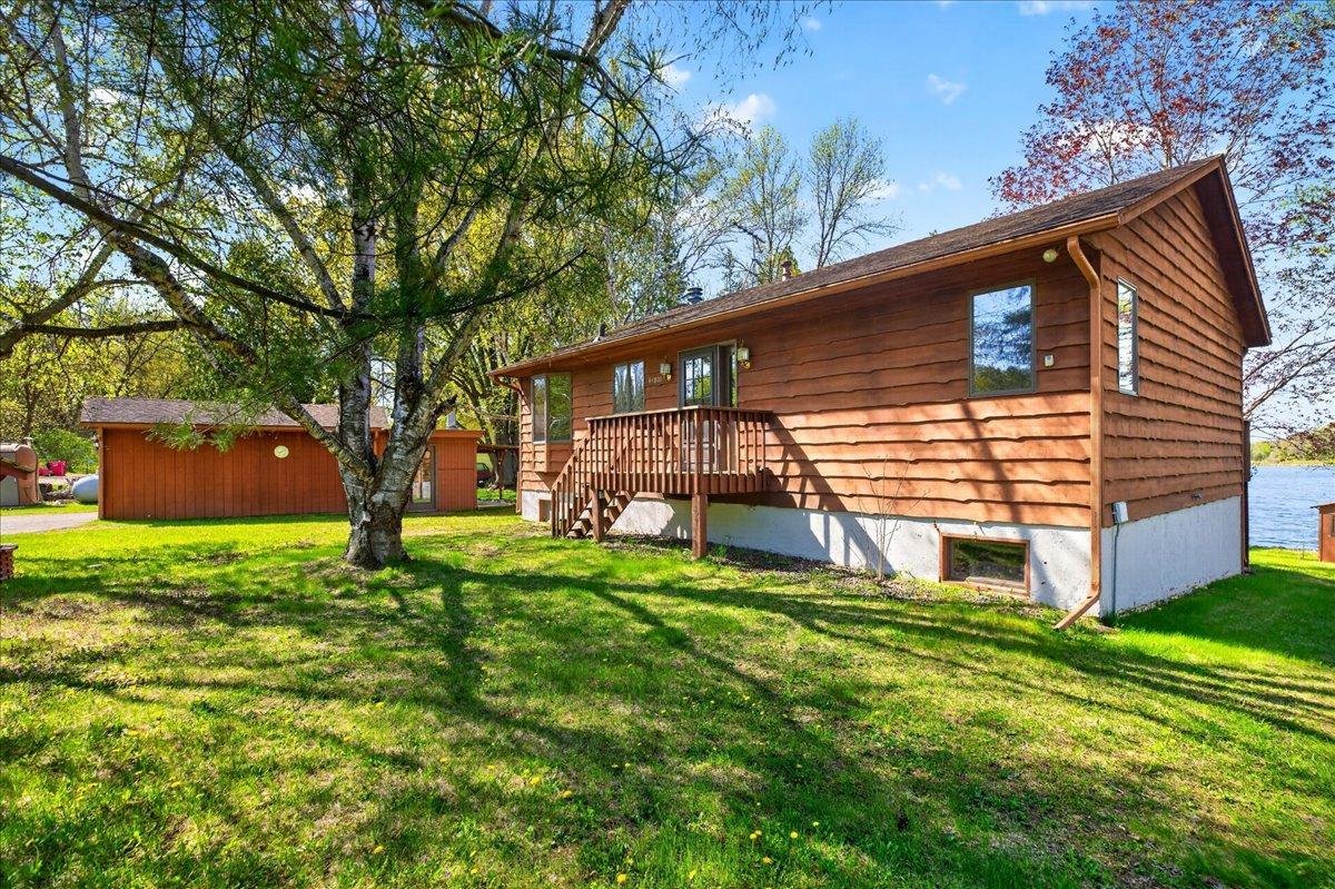 Side view of the home showcasing the spacious yard, mature landscaping, and detached garage space.
