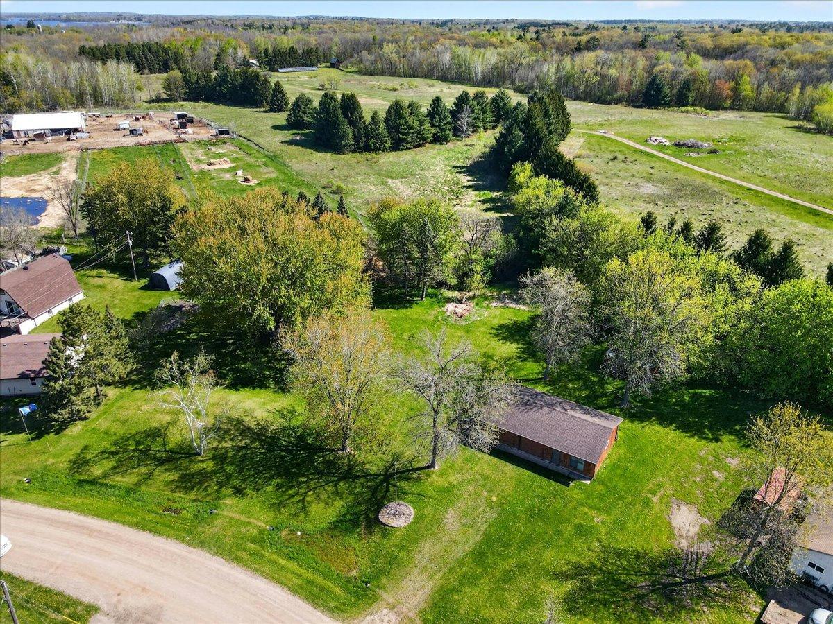 Aerial view showcasing the additional parcel across the road featuring the spacious detached 3-car garage and large yard area.